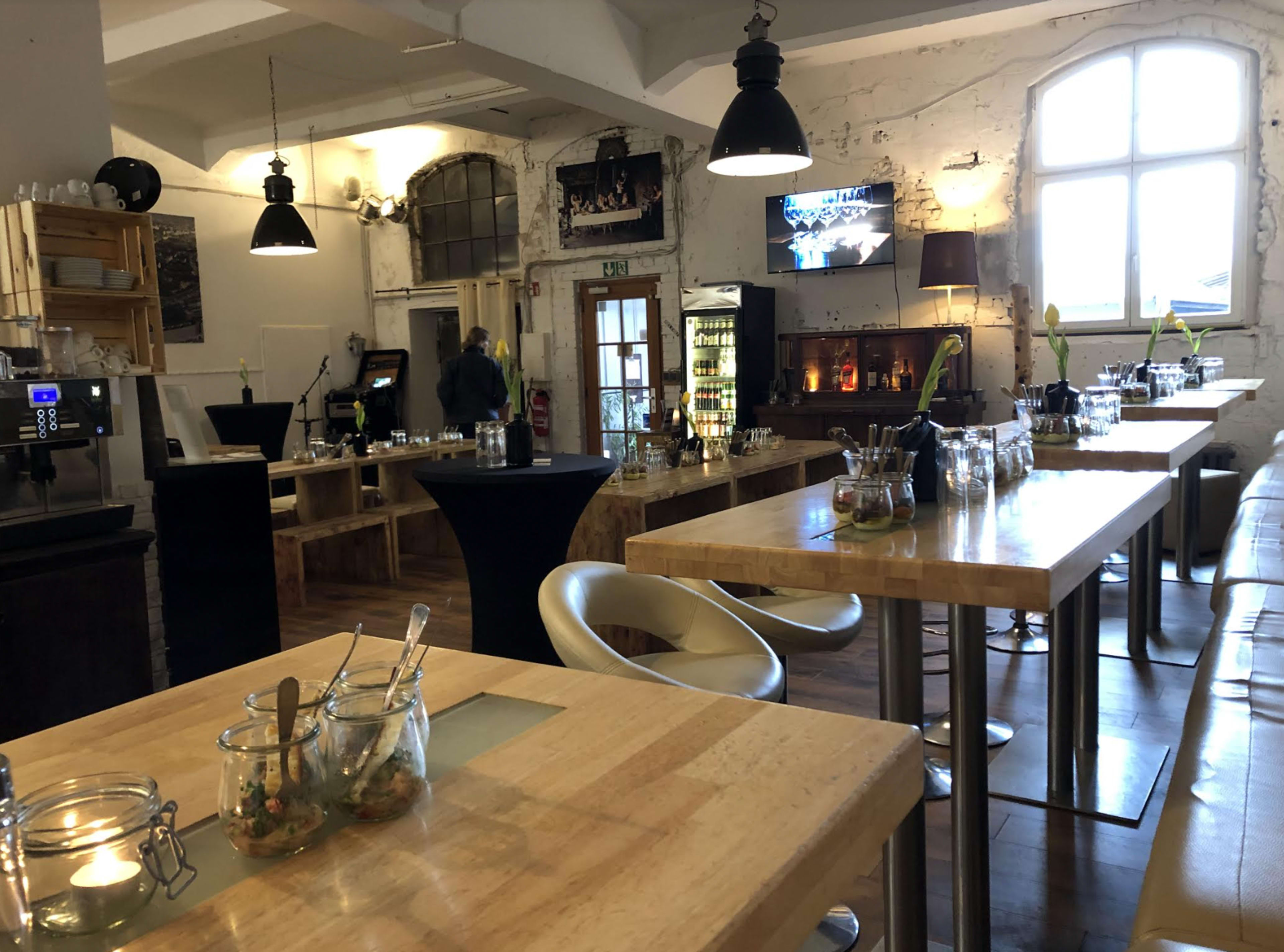 A modern restaurant interior with wooden tables, minimalist decor, and a serving counter in the background.