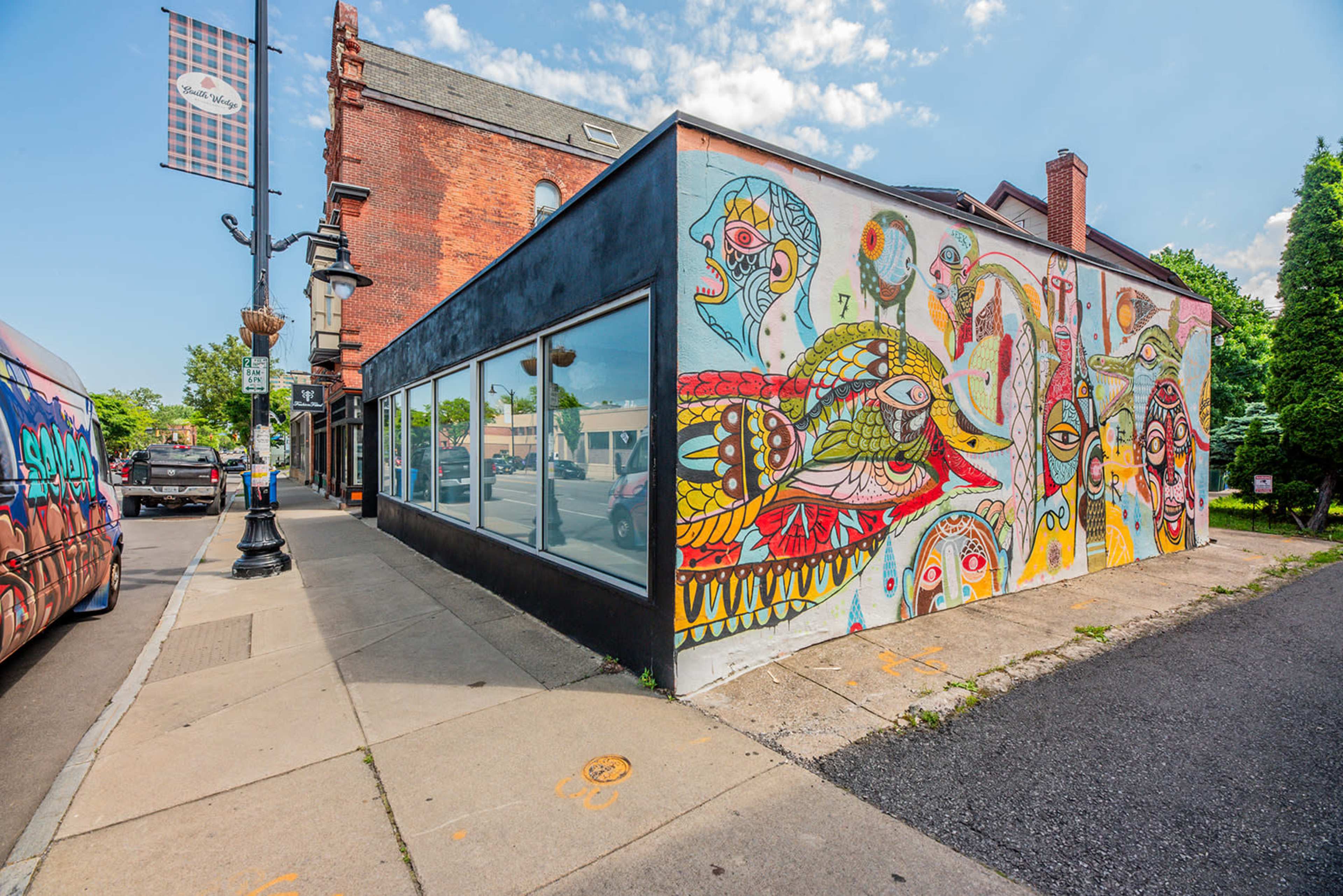 A building corner features a mural with colorful and abstract designs on one of its walls.