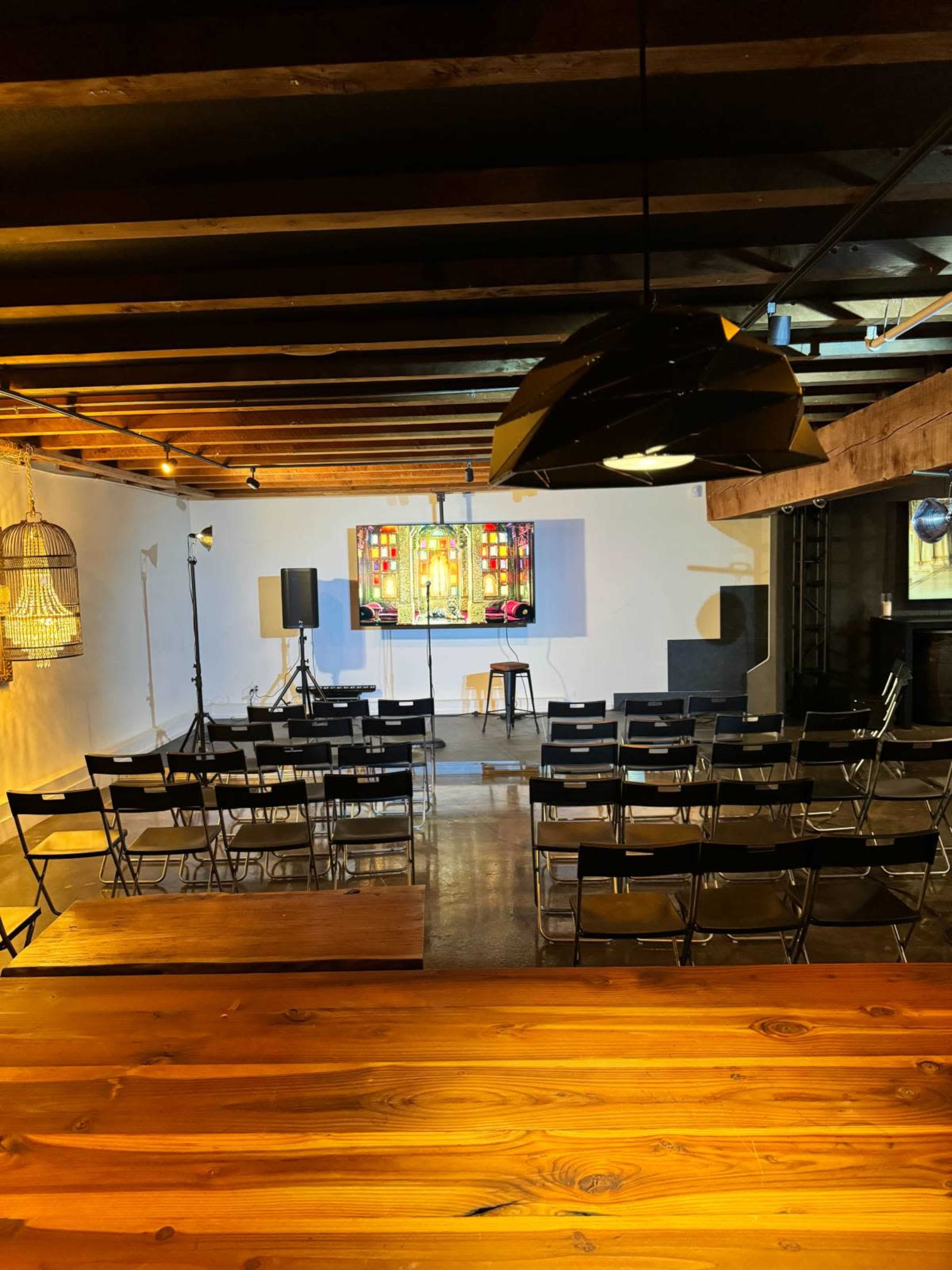 The image shows a venue set up for a presentation, featuring rows of chairs facing a backdrop with stained glass windows and a stage area.