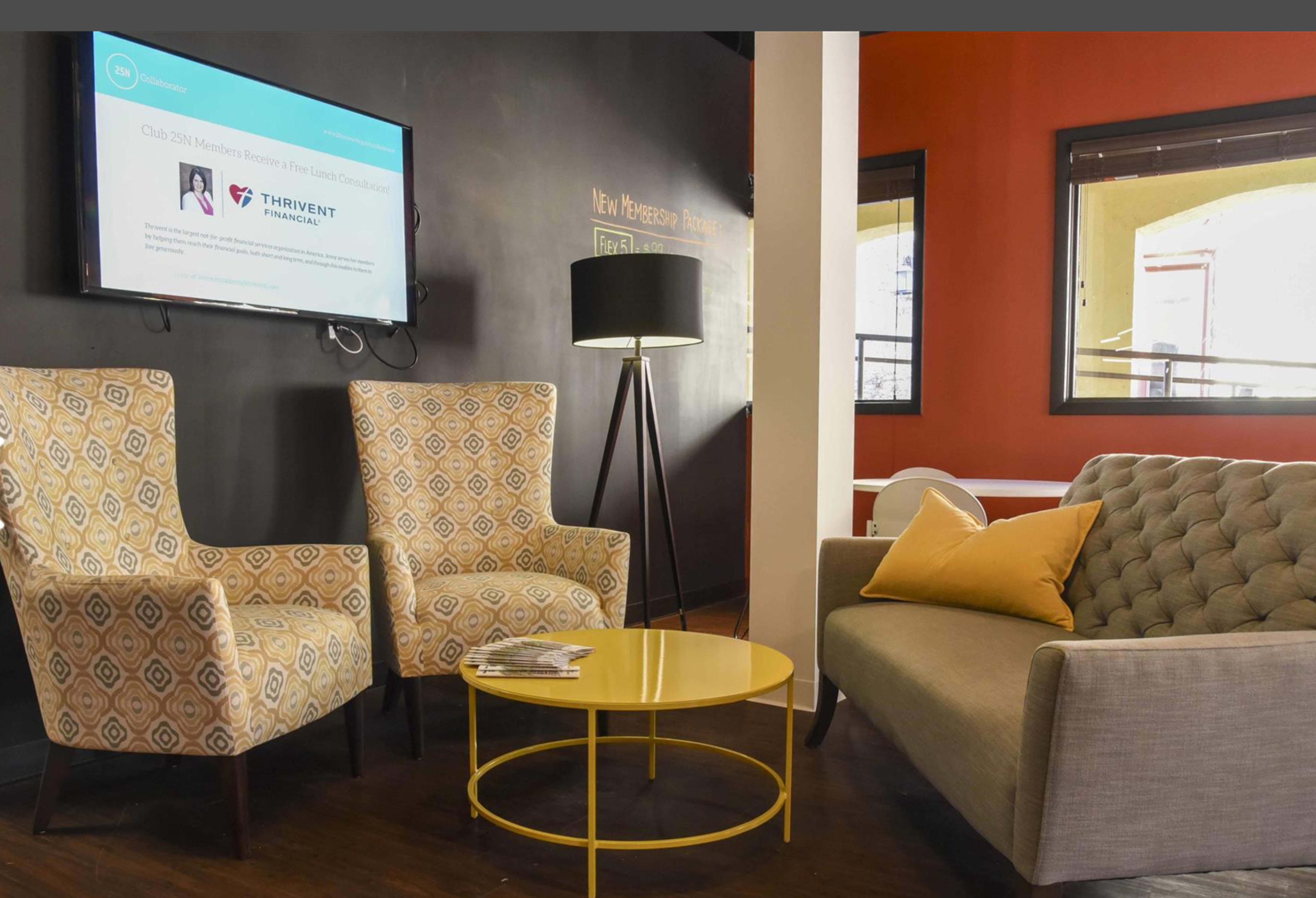 A modern seating area with two patterned armchairs and a gray sofa, accompanied by a yellow coffee table and a black floor lamp, against a backdrop of contrasting wall colors.