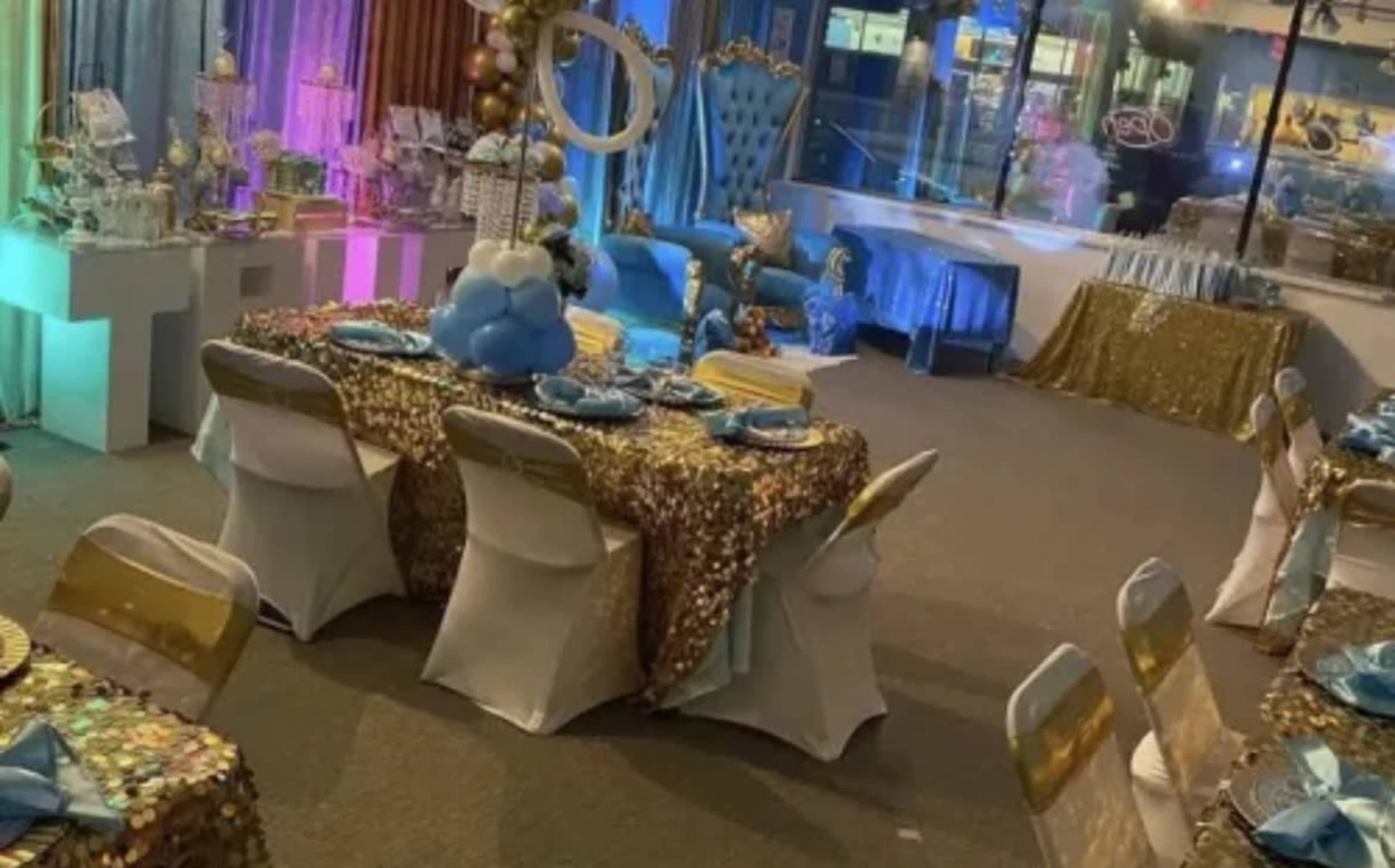 A banquet hall set up for a celebration with tables adorned in sequined tablecloths, thematic decorations, and colorful lighting.