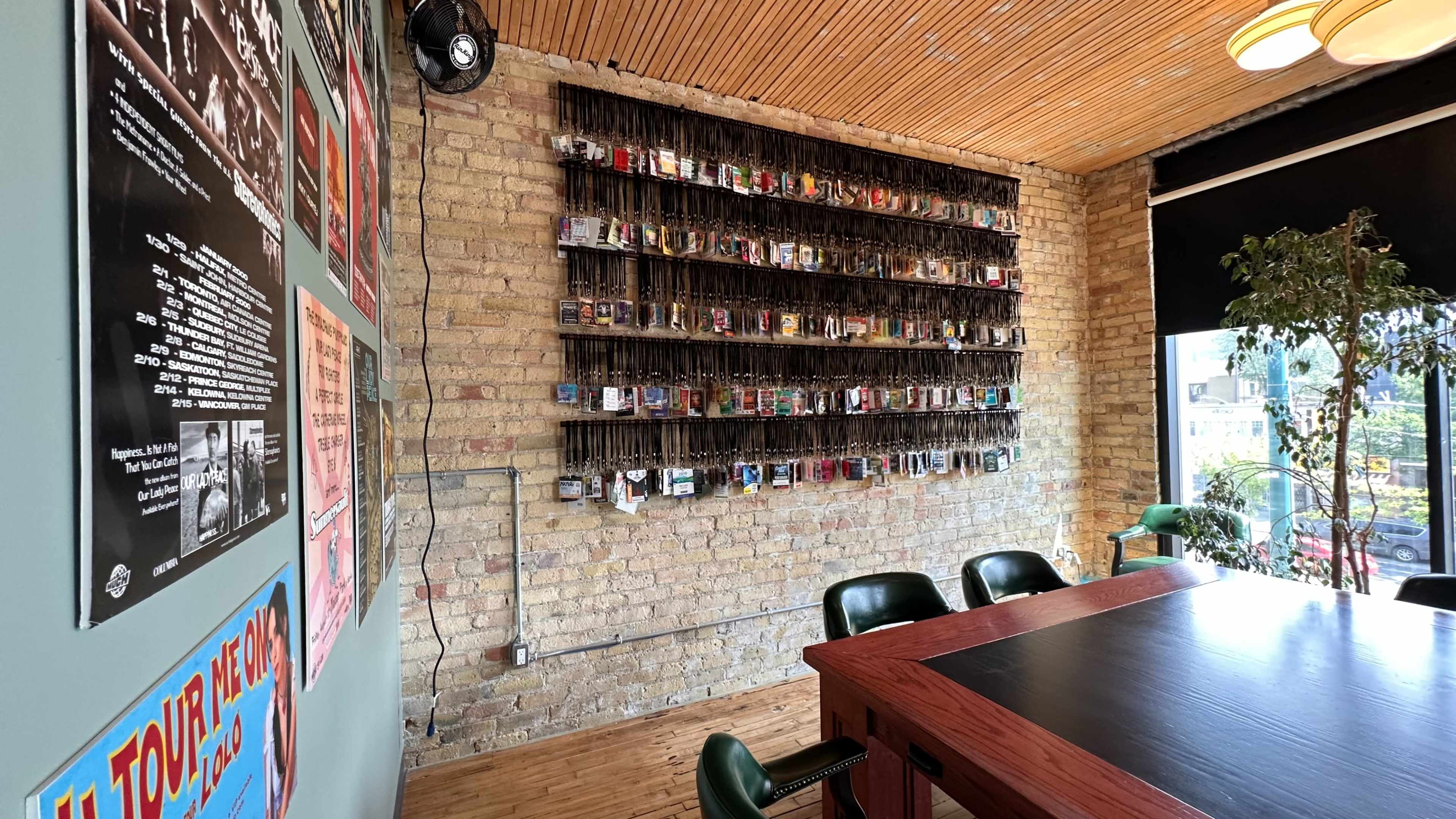 The image shows a wall with a shelf displaying various colorful items, set in a room with wooden paneling and a large table surrounded by chairs.