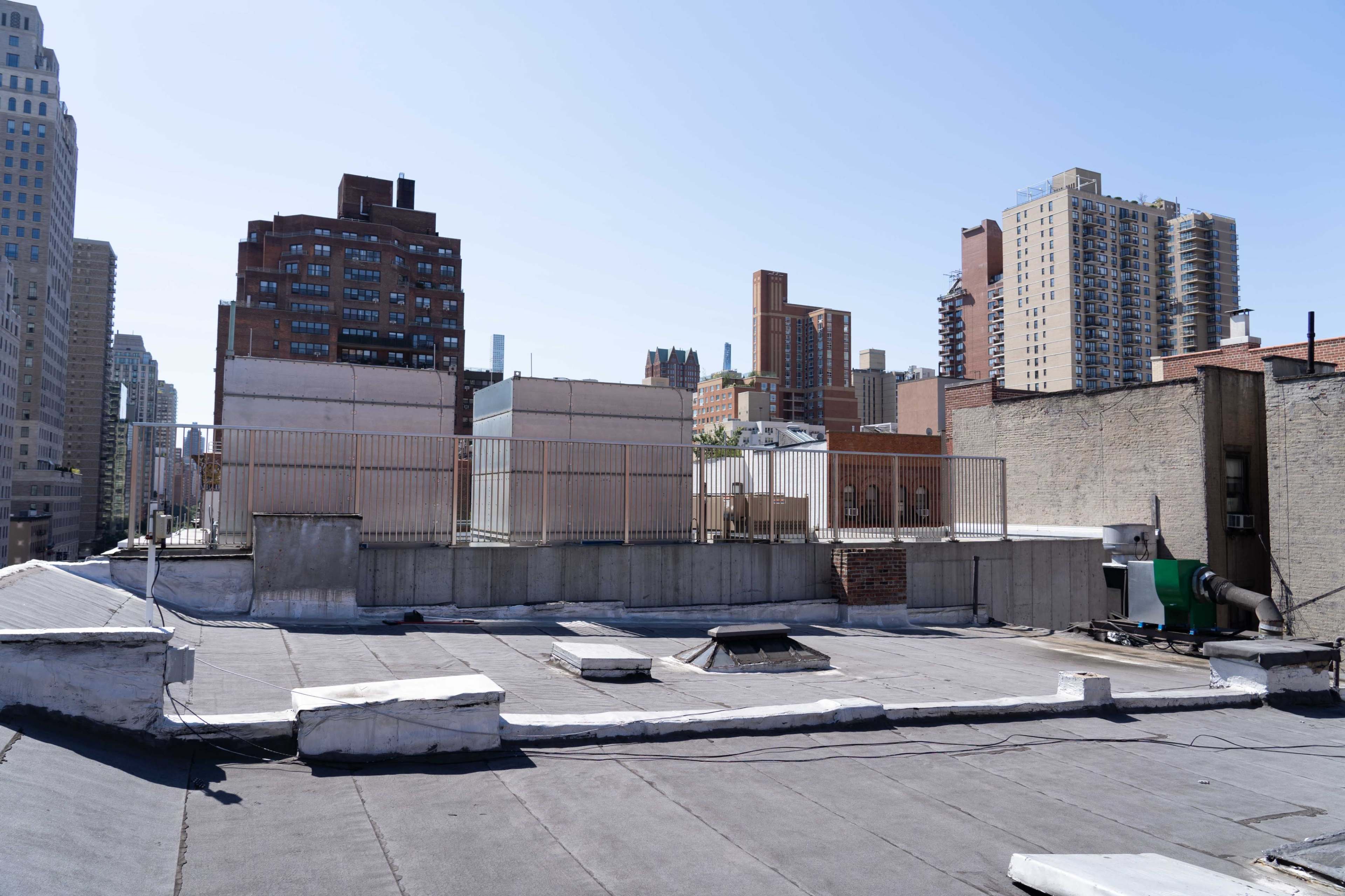 A rooftop view featuring various buildings and a clear blue sky in an urban setting.