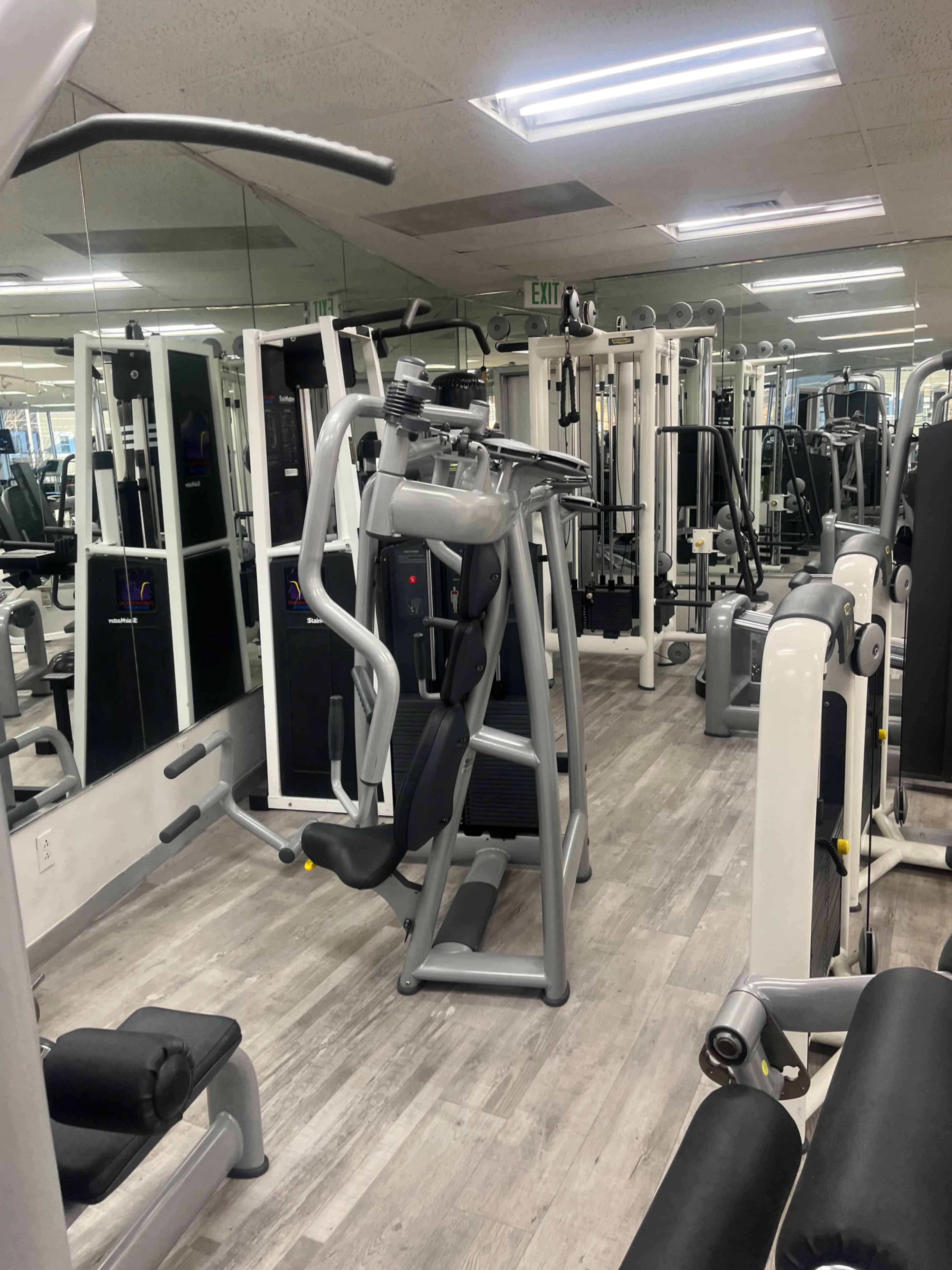A well-equipped gym with various exercise machines and mirrors on the walls.