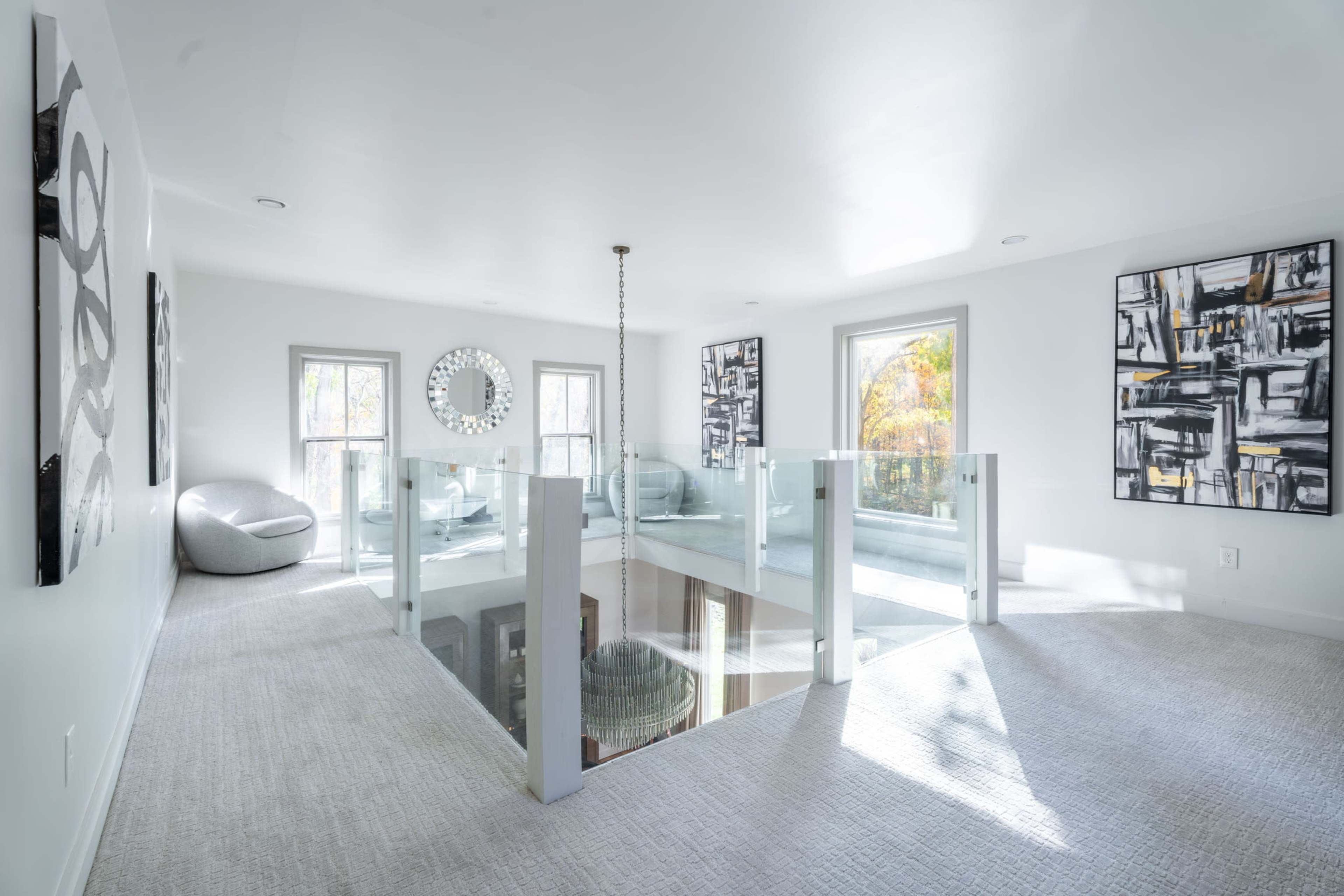 A bright, modern loft space with glass railings and contemporary artwork on the walls.