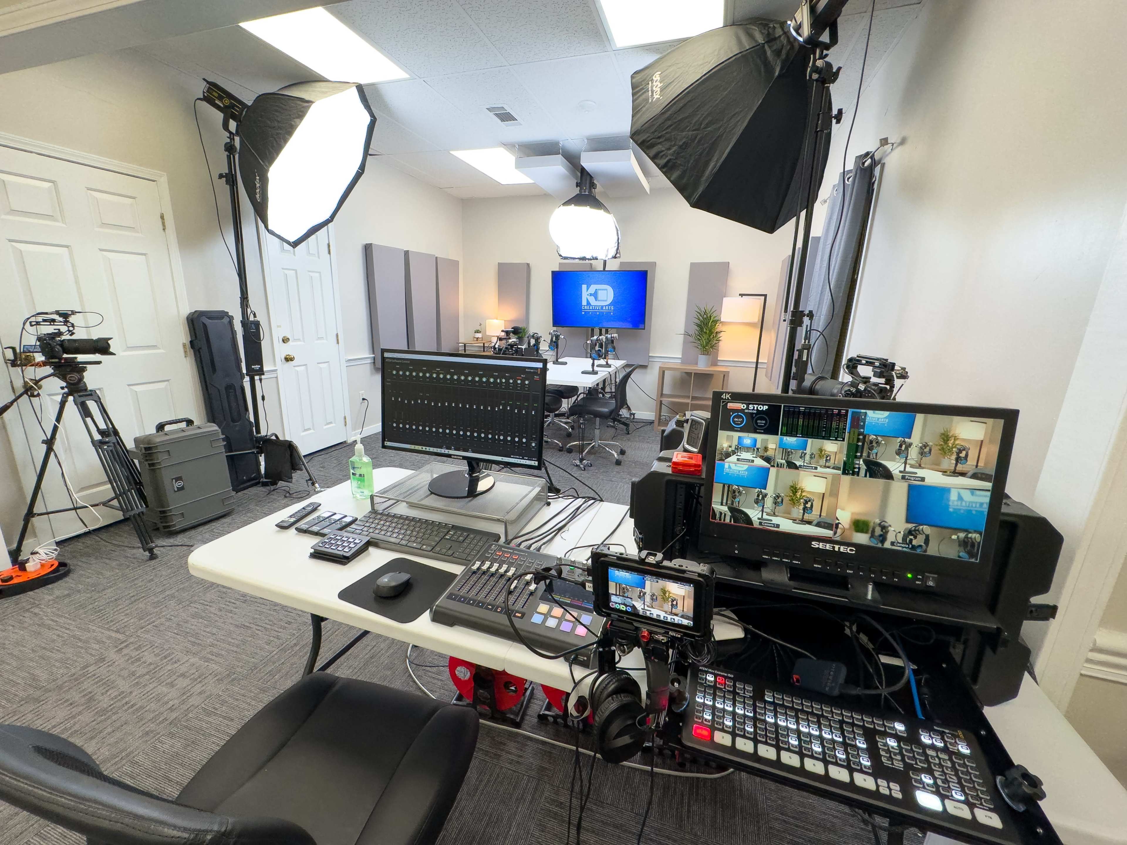 A well-equipped video production studio with multiple cameras, lights, and a control desk featuring monitors and equipment for live editing.