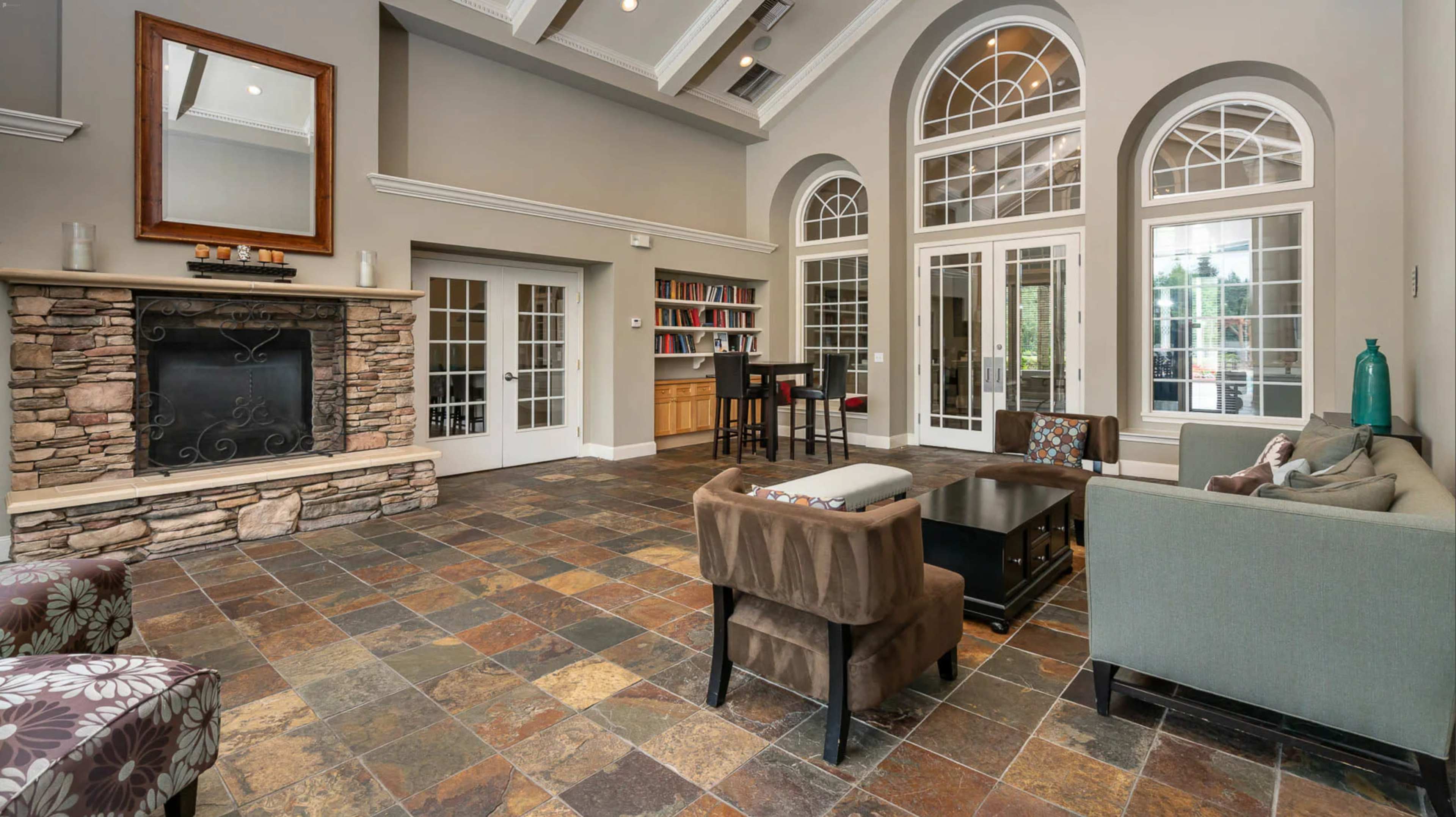 A spacious living area with a stone fireplace, large arched windows, and comfortable seating arranged around a coffee table.