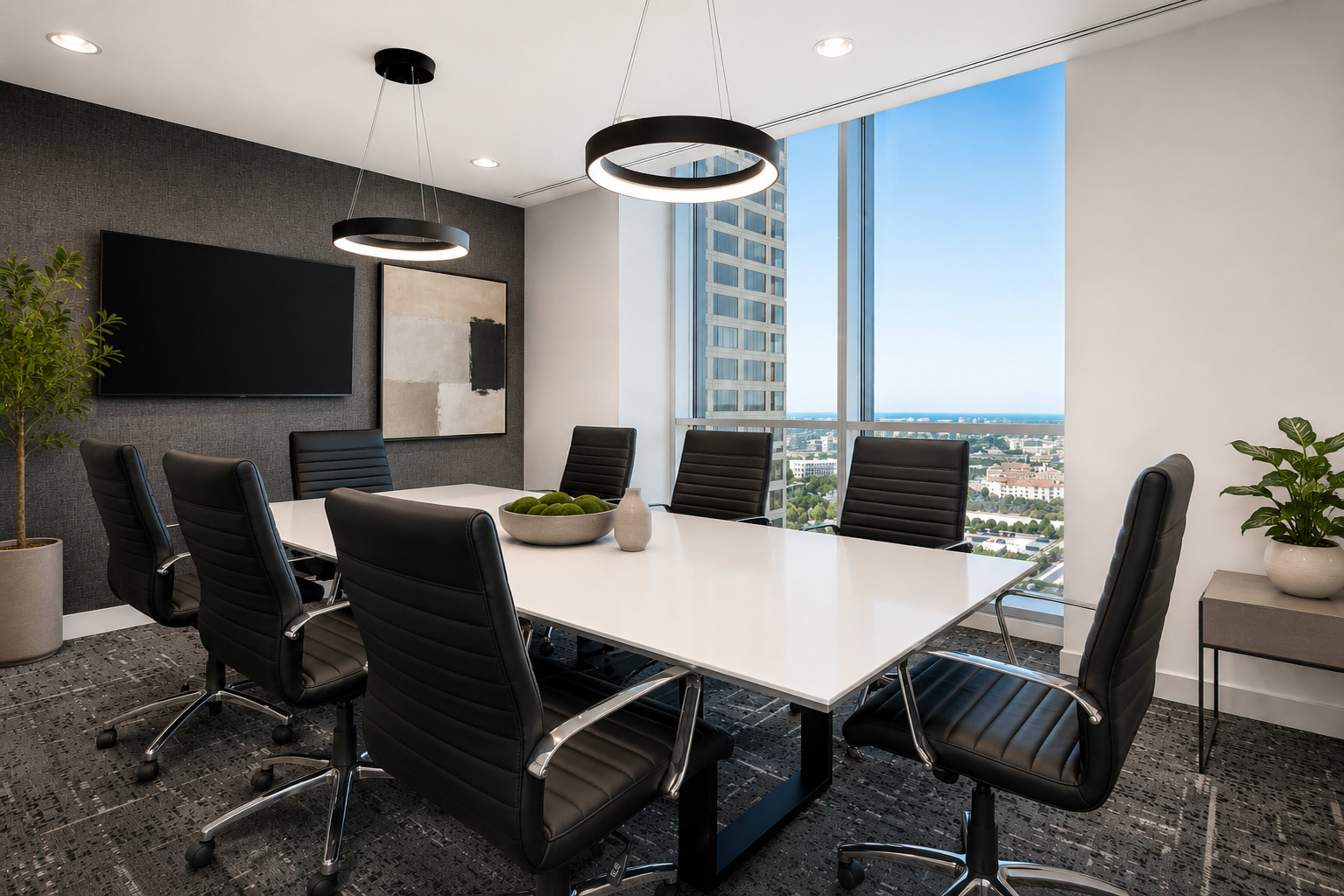 A large, modern conference room features a white table surrounded by black ergonomic chairs, with large windows showcasing a city view.