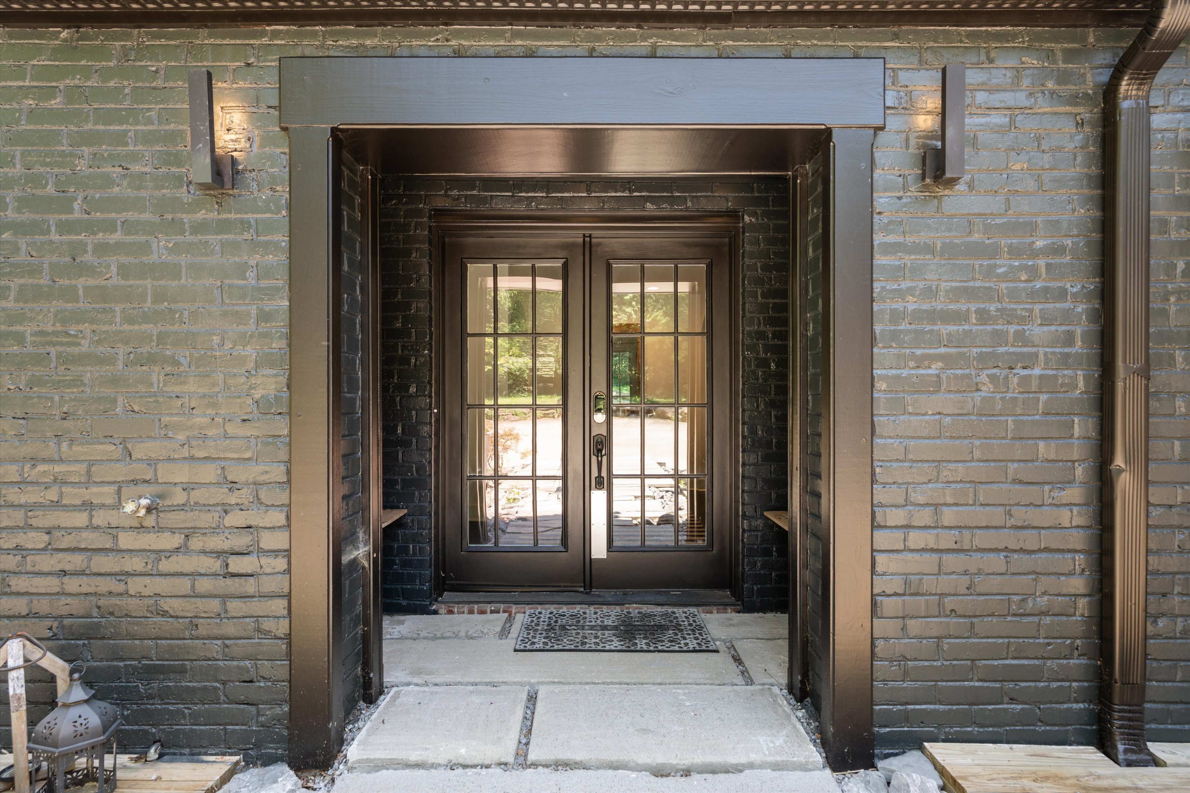 The image shows a pair of glass-paneled double doors set in a dark-brick entryway.