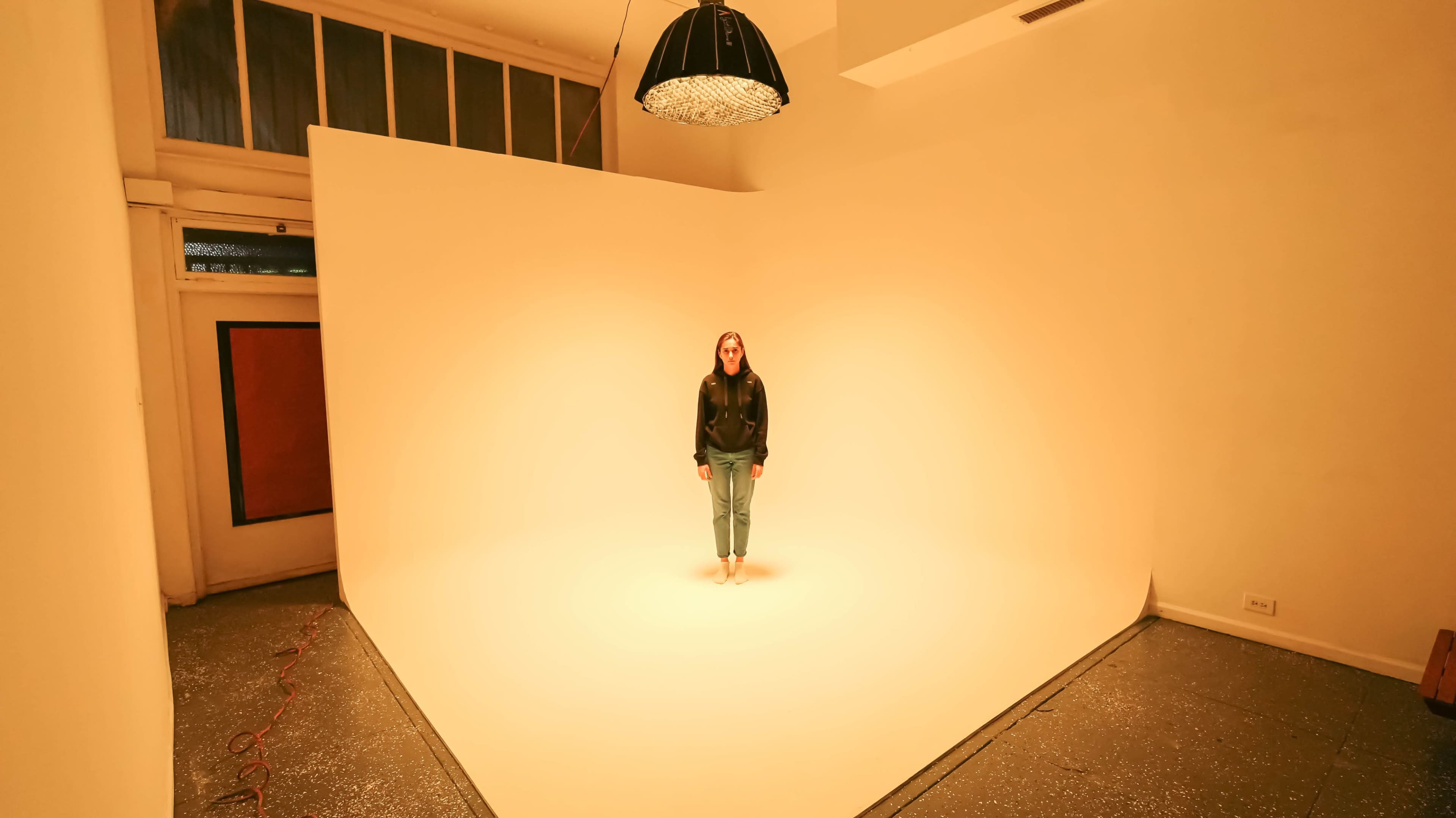 A person stands in a well-lit studio against a large, curved light-colored backdrop.