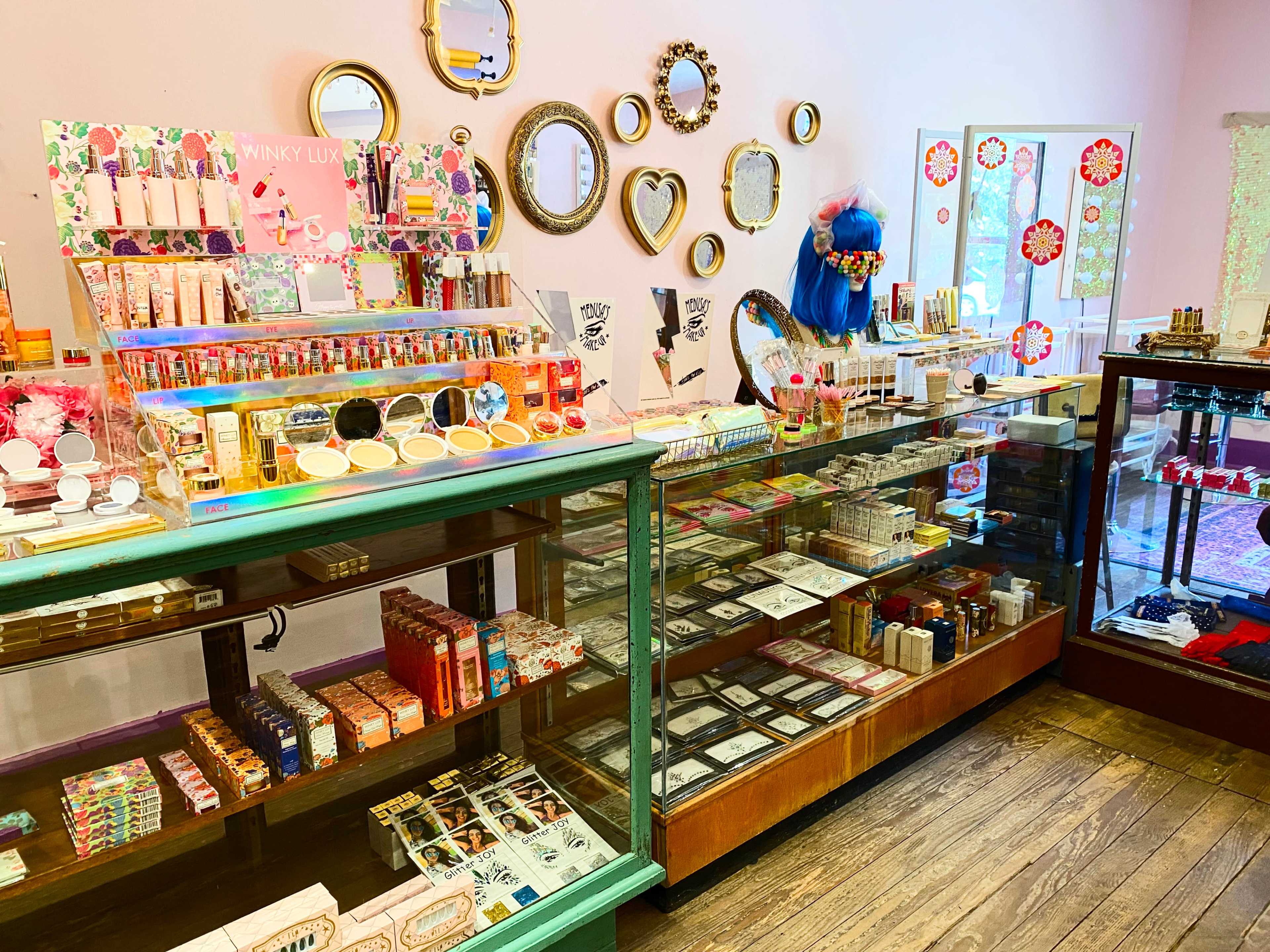 The image shows a brightly decorated cosmetics store with various makeup products displayed on shelves and in glass cases.