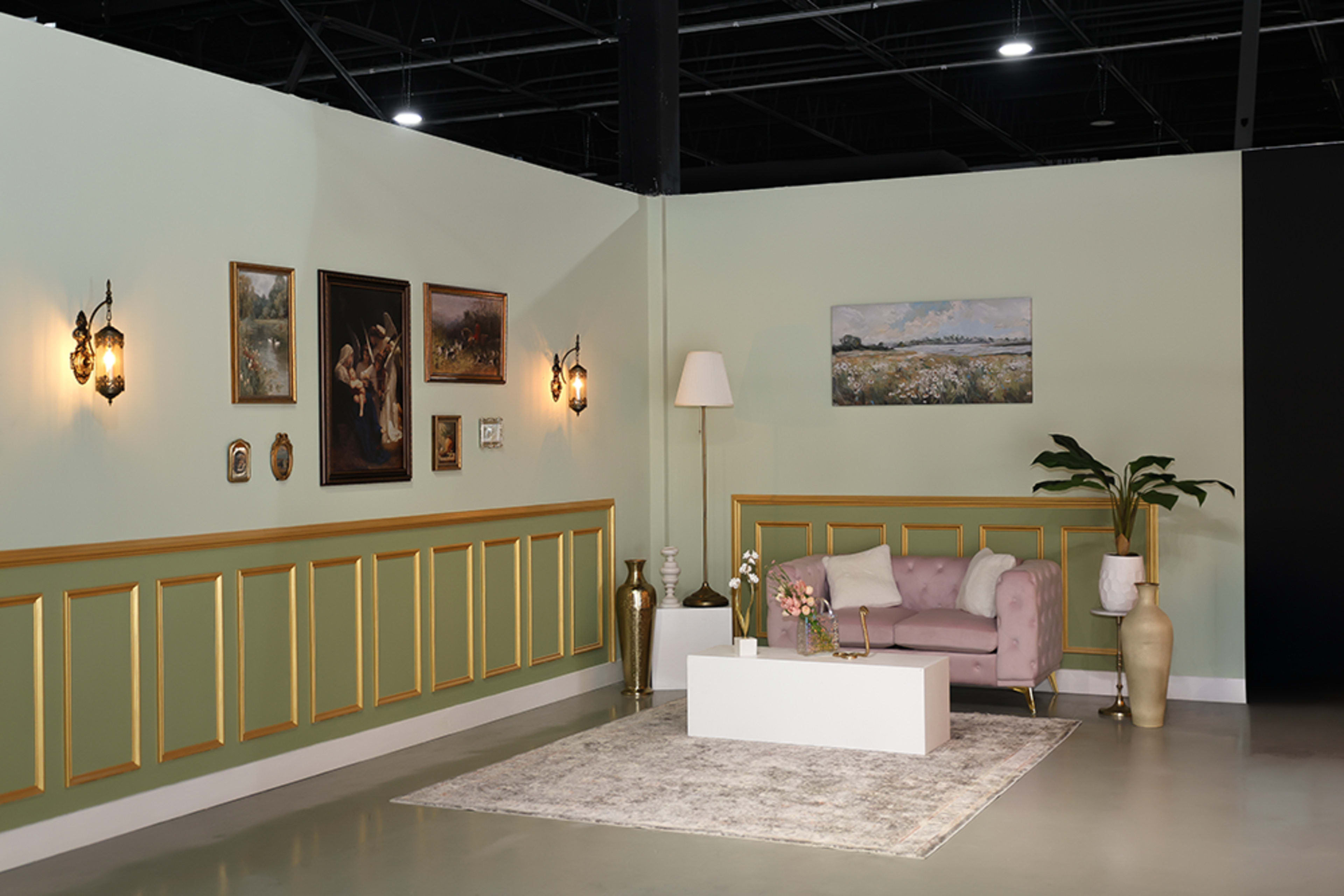 The image shows a modern interior scene with a purple sofa, a white coffee table, wall decorations, and plants in a well-lit room featuring green and black walls.