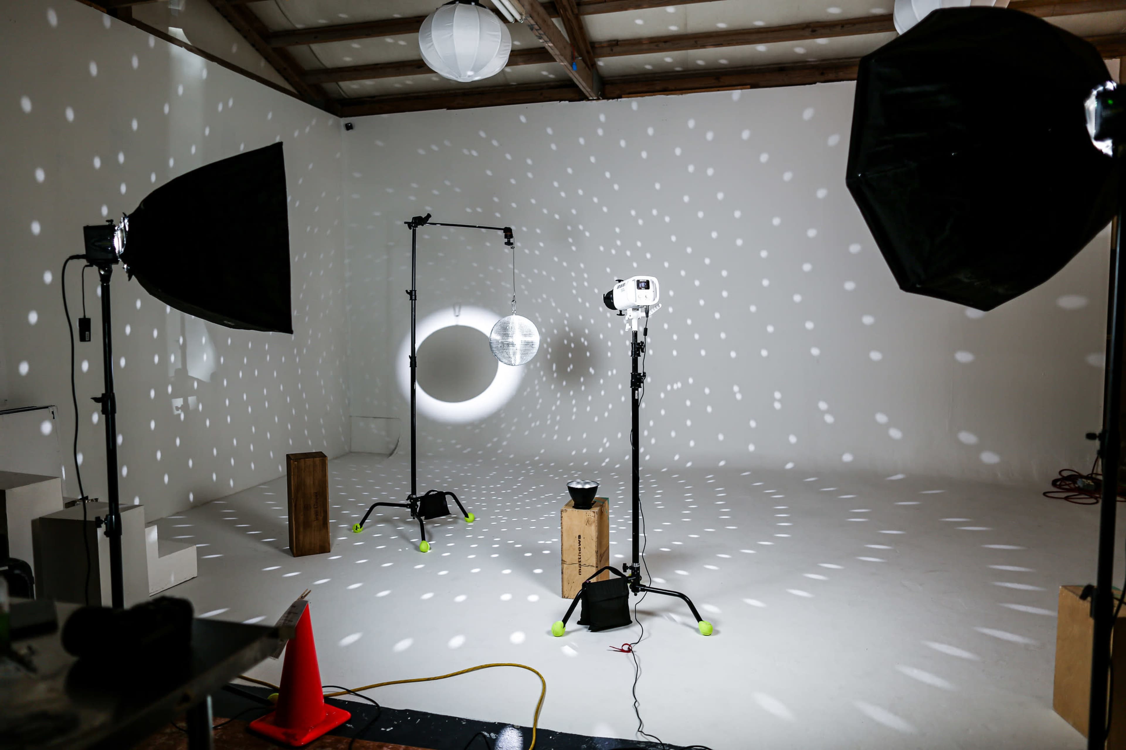 A photography studio with lighting equipment arranged around a white backdrop, casting circular patterns of light on the floor.