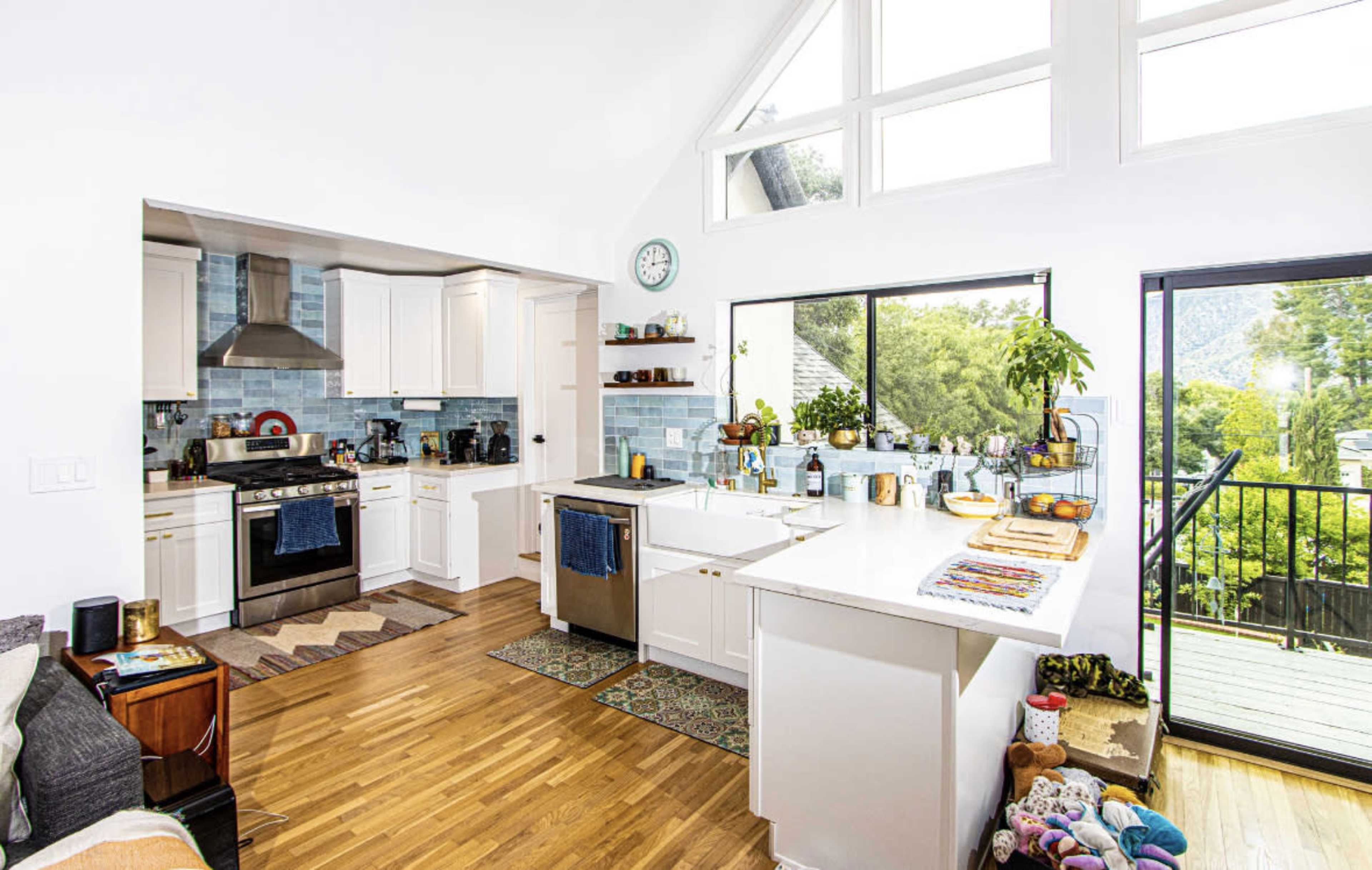 A bright, open kitchen with white cabinetry, a central island, and large windows allowing natural light to illuminate the space.