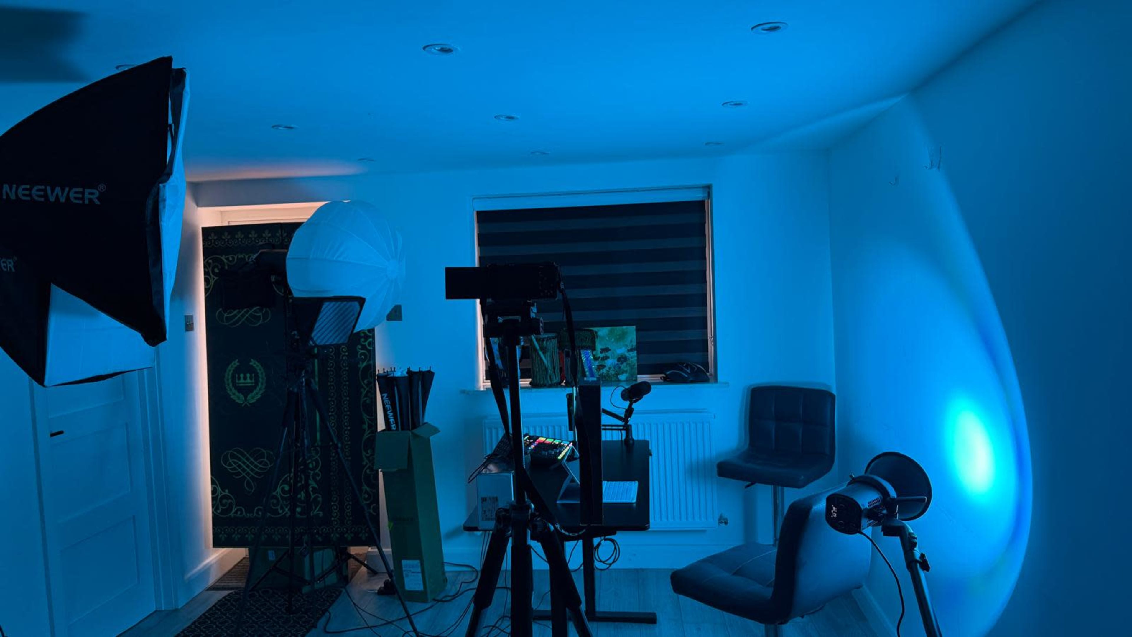 A dimly lit room equipped with photography lighting, a chair, and a decorative panel on the wall.