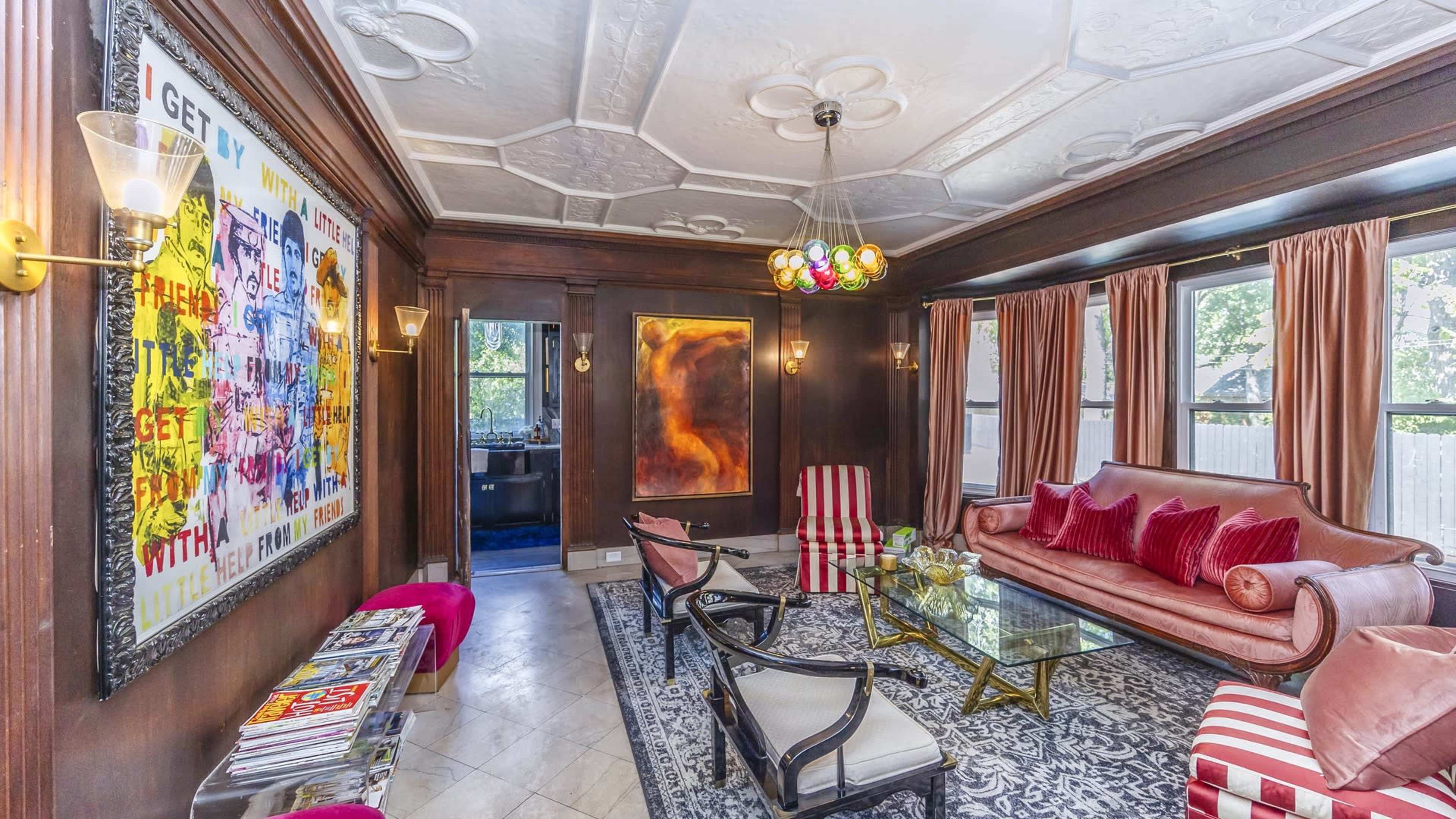 A stylish living room featuring a leather sofa, armchairs, a coffee table, and decorative art on the walls.