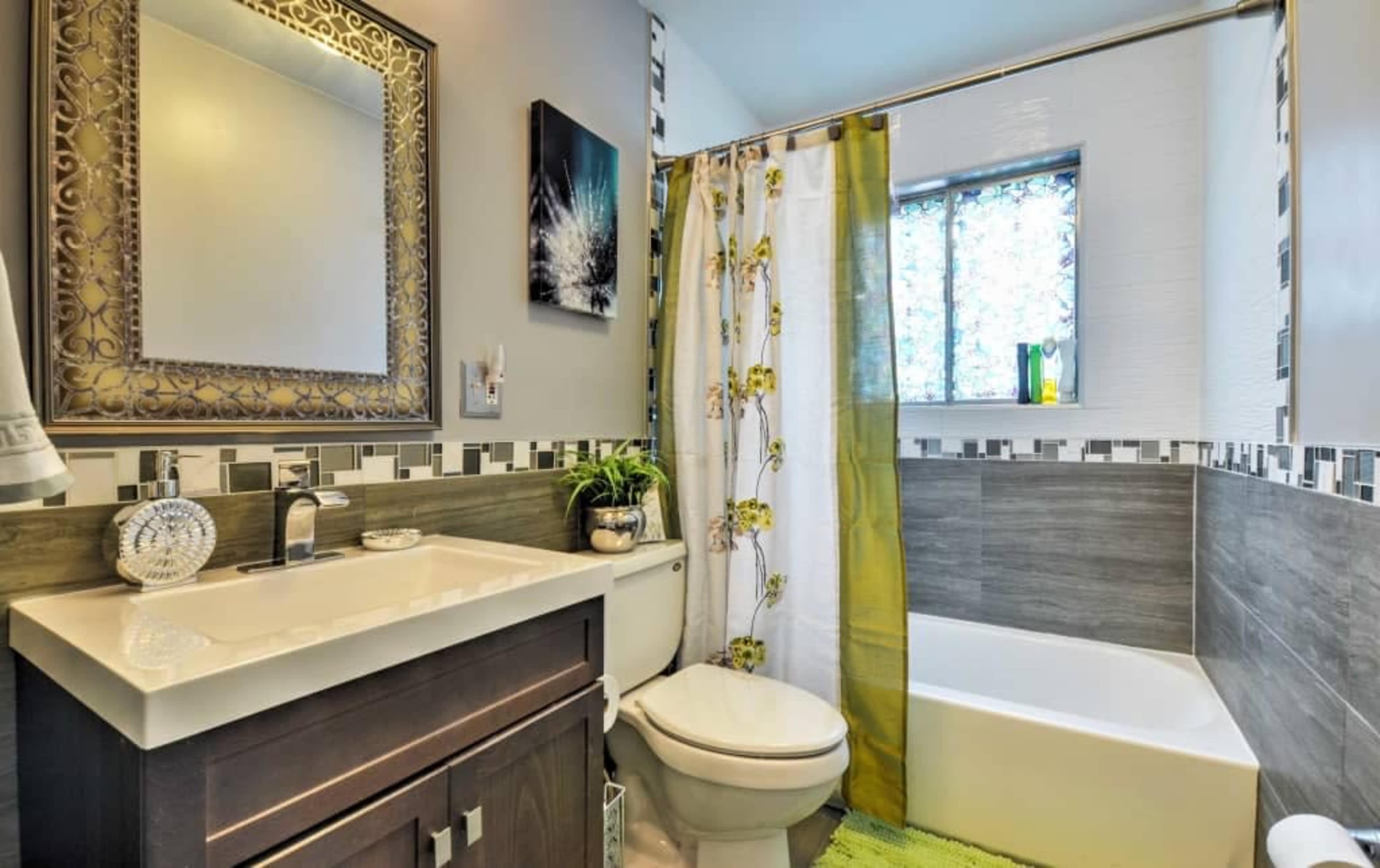 A modern bathroom featuring a white tub, a dark wood cabinet with a sink, and a shower curtain with floral patterns.