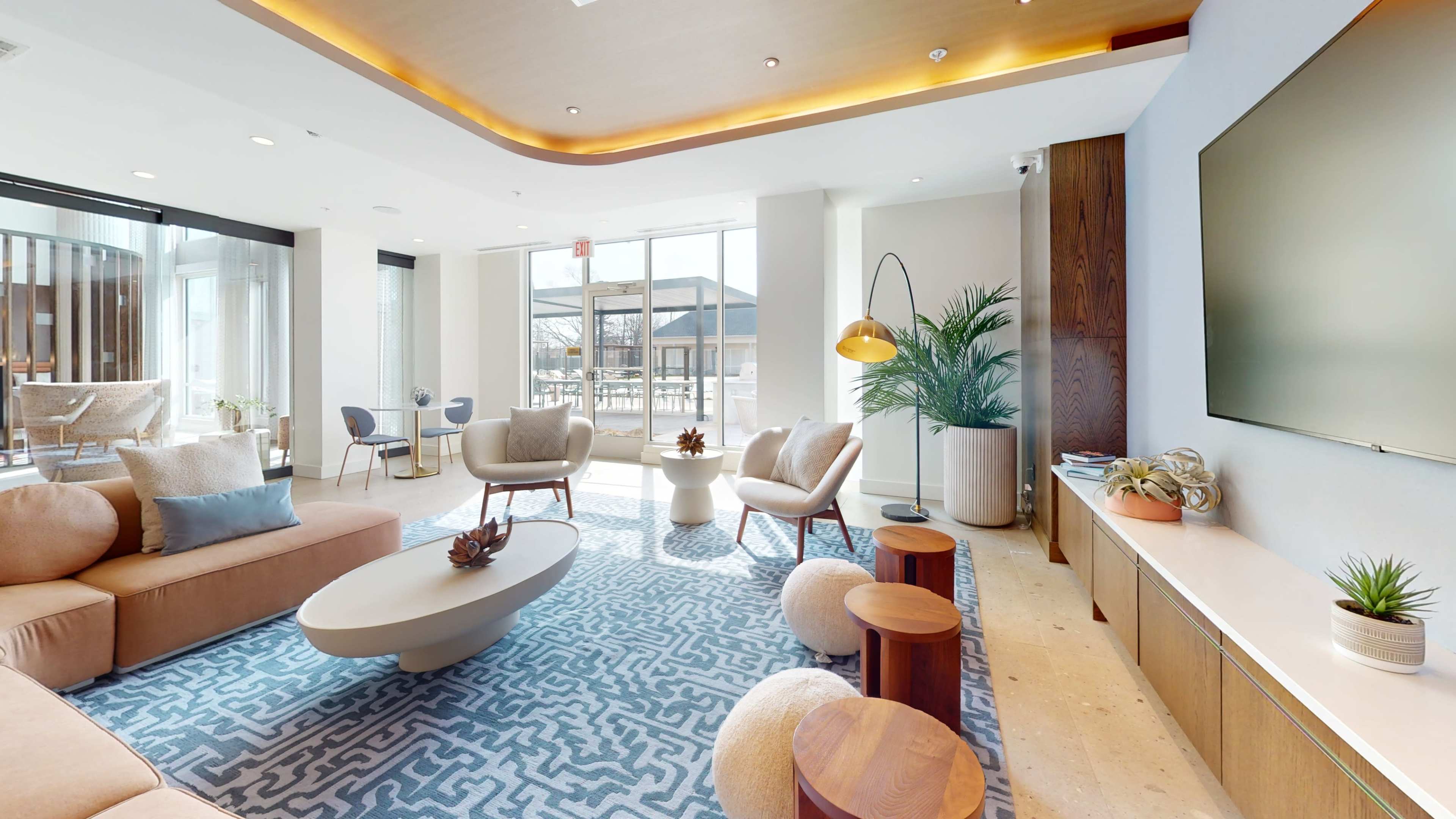 A modern lounge area features comfortable seating, a coffee table, and a large window allowing natural light to fill the space.