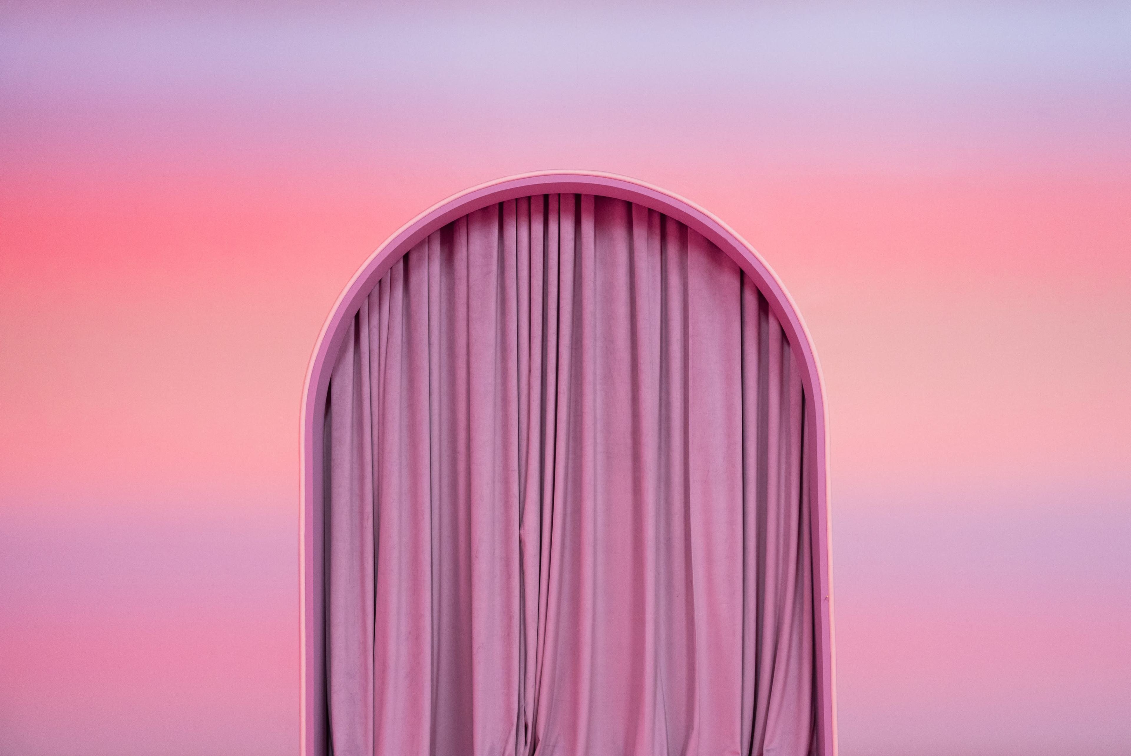 A soft pink archway frames flowing curtains against a gradient pink background.
