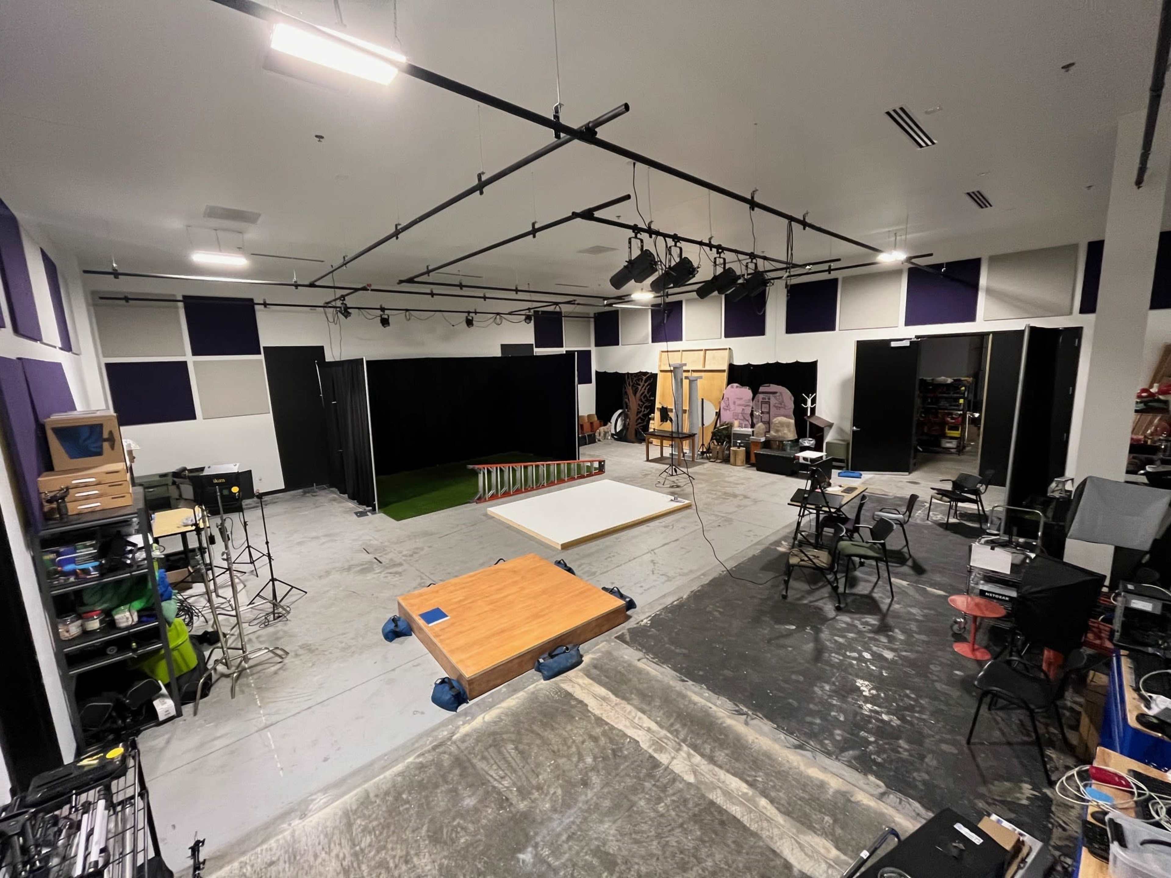 A large studio space with various equipment, including lighting fixtures, set pieces, and multiple workstations.