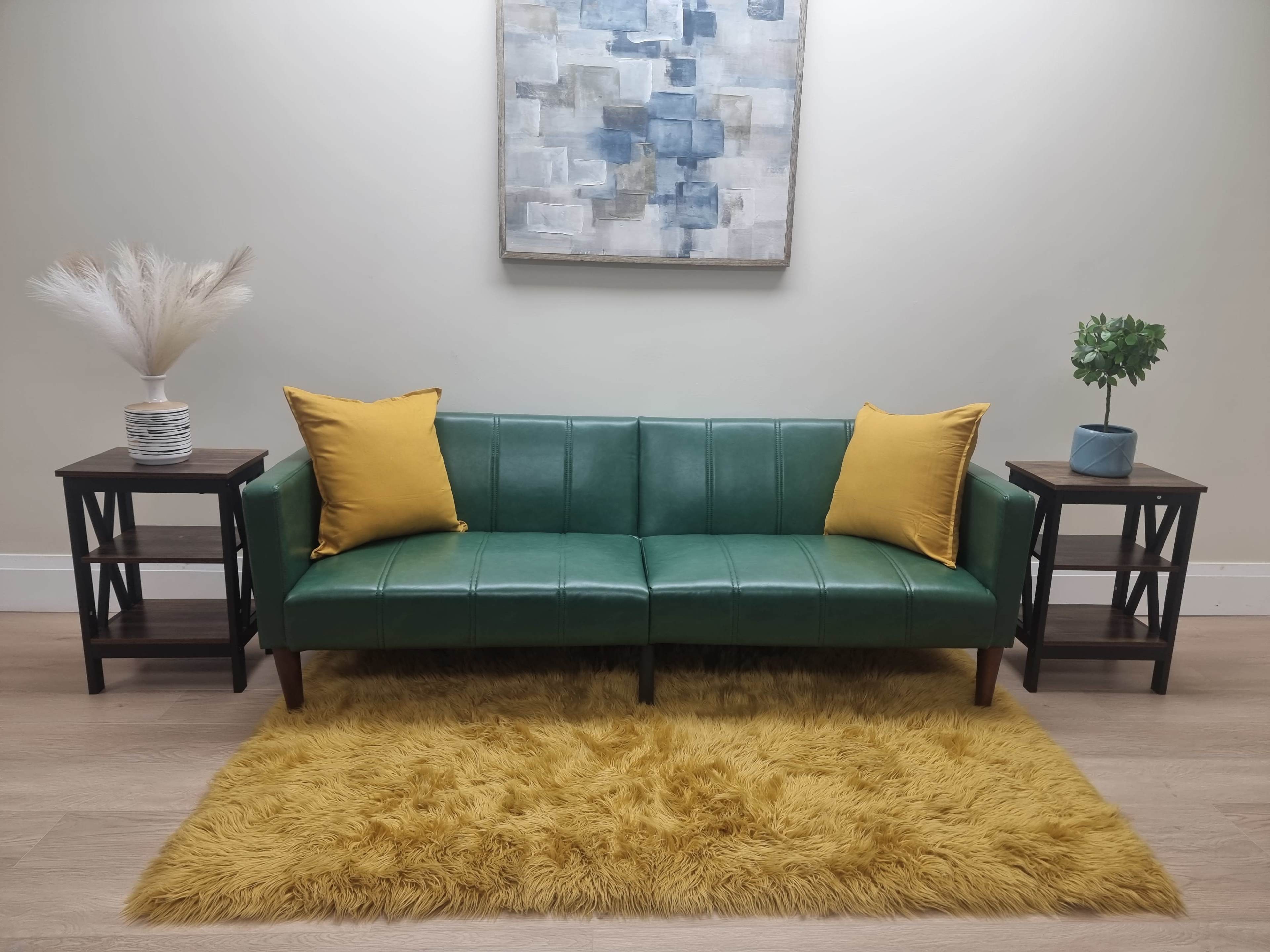 A green sofa with yellow cushions is centered between two dark wooden side tables, all positioned on a fluffy yellow rug against a light-colored wall.