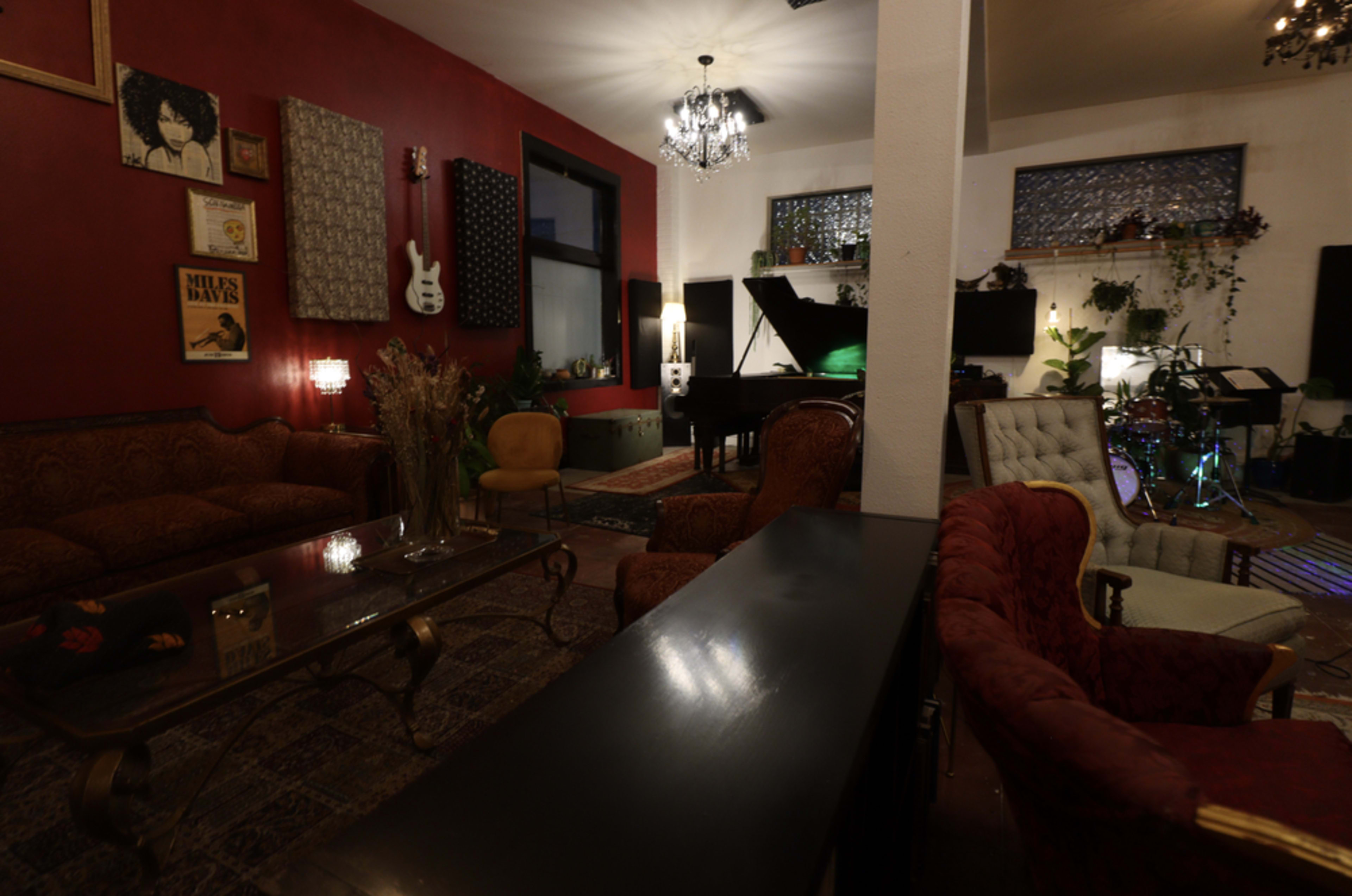 A stylishly decorated room featuring a piano, various seating arrangements, and musical instruments.
