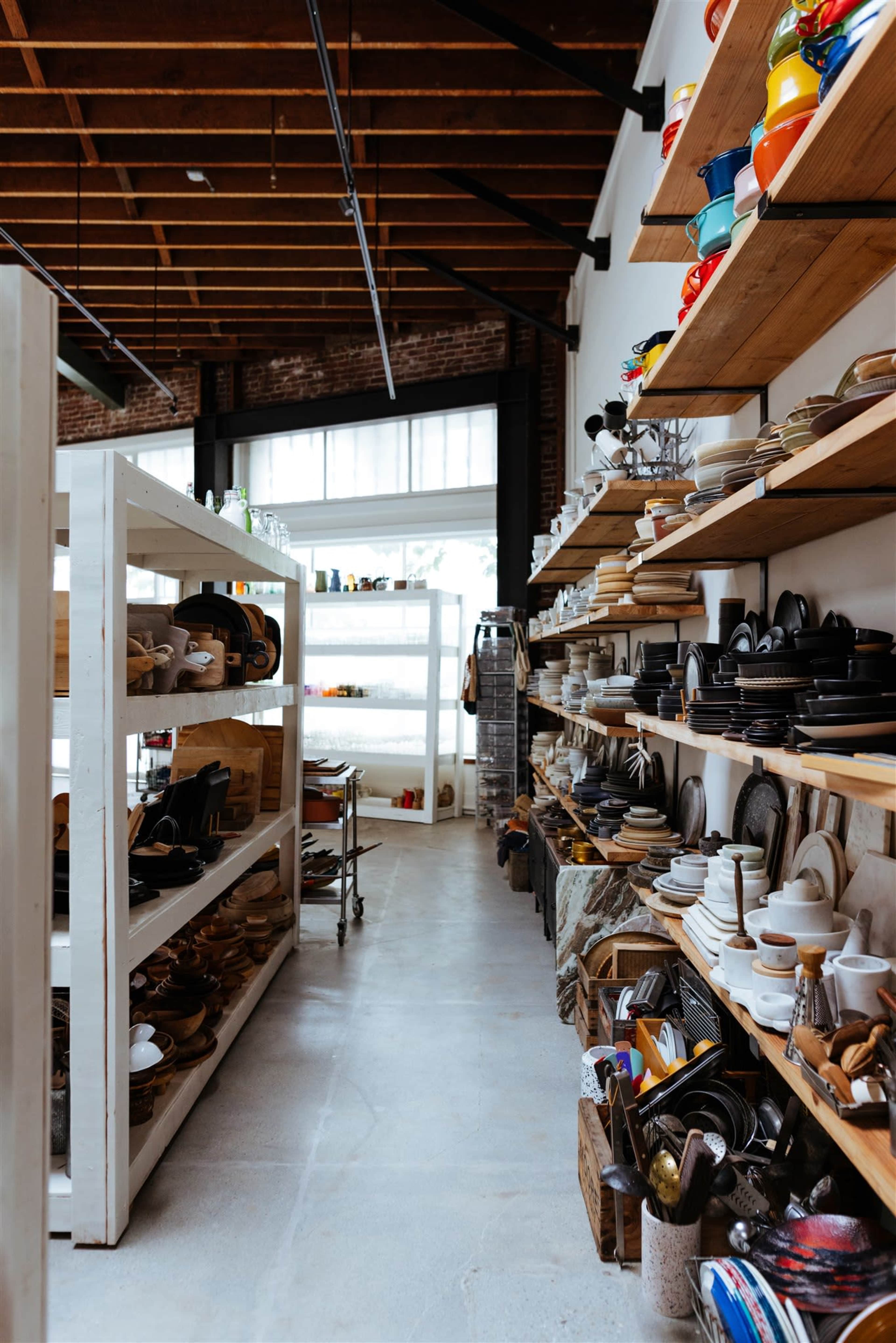 An aisle in a store filled with neatly organized shelves displaying various kitchenware and cookware items.