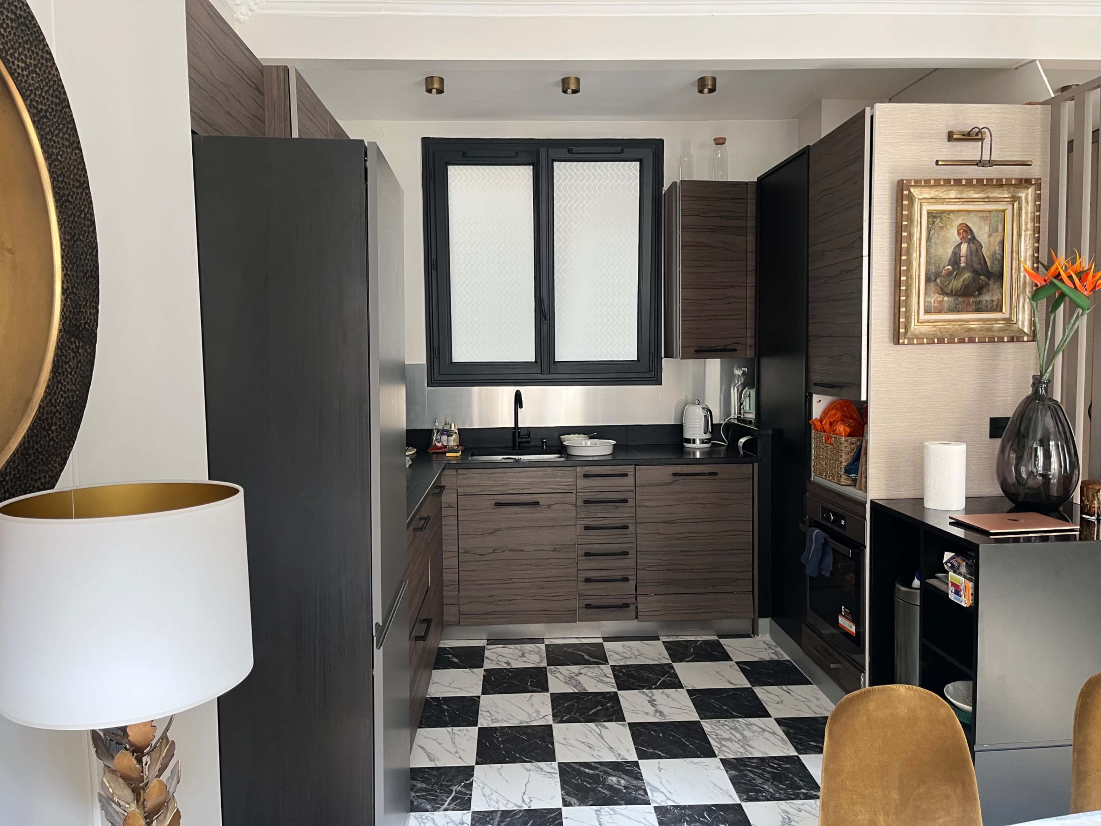 The image shows a modern kitchen with dark wood cabinetry, black countertops, and a black and white checkered floor.