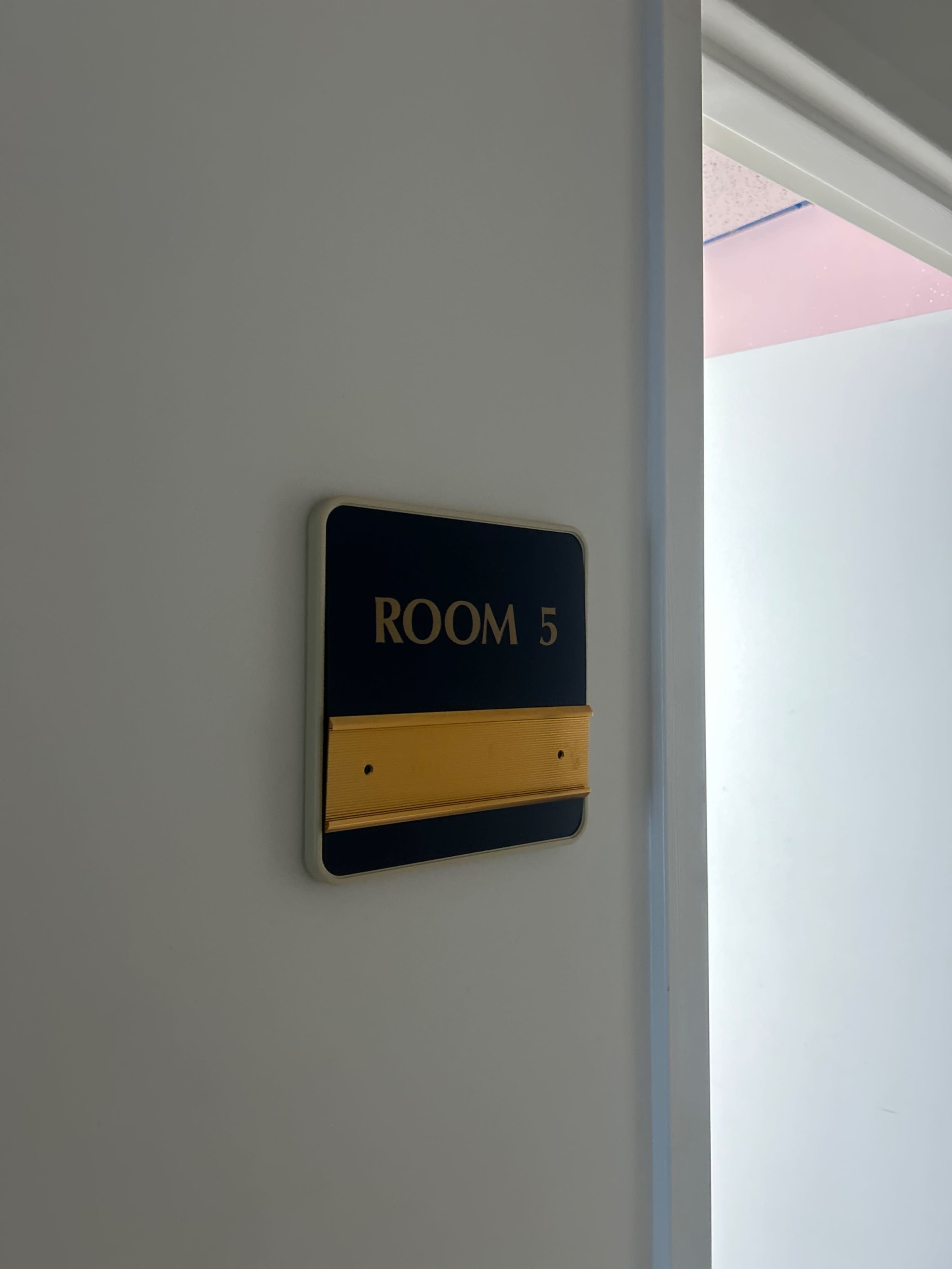 A sign labeled "ROOM 5" is mounted on a wall beside an open door.