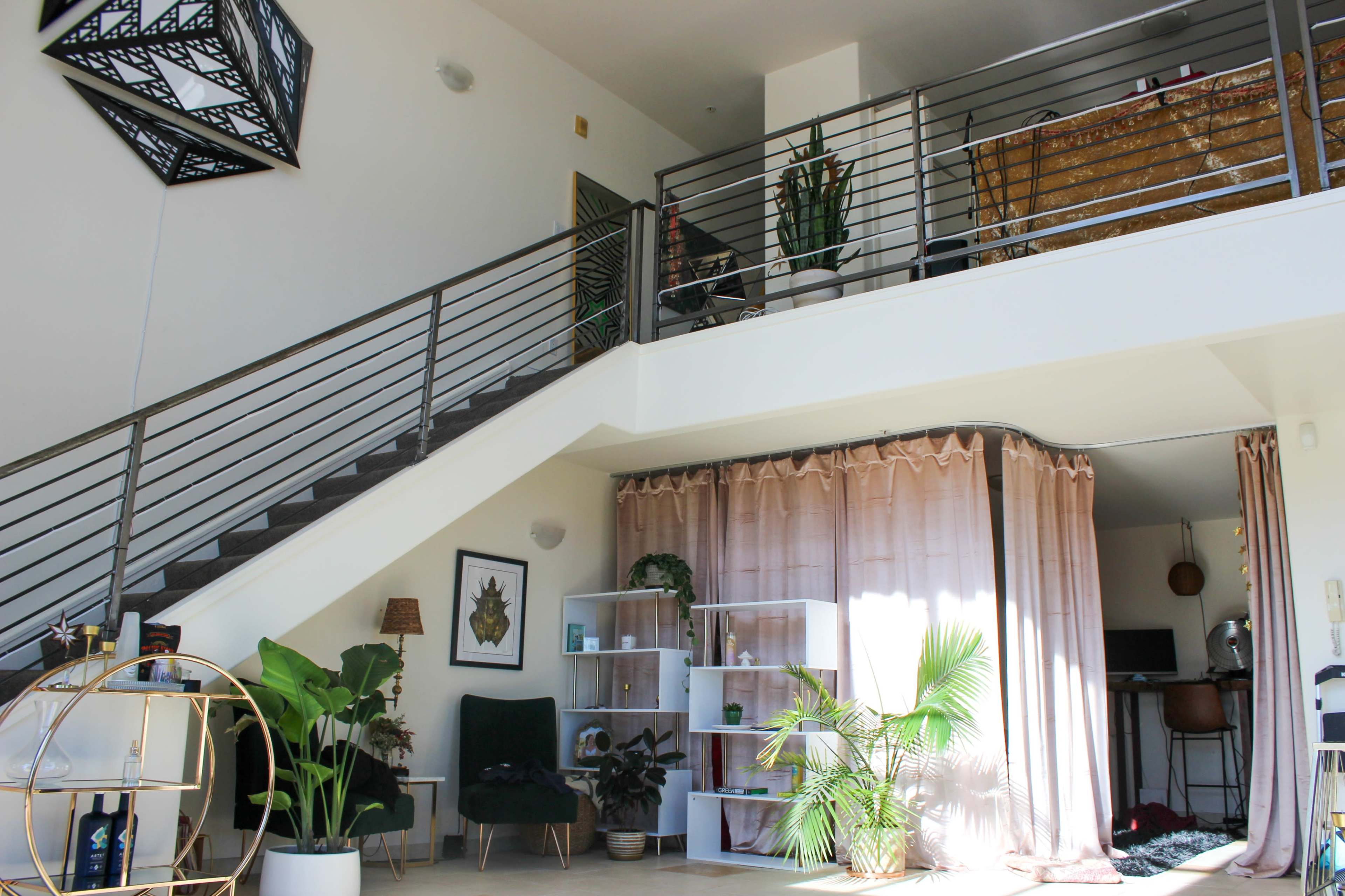A two-level living space with a staircase, plants, and a blend of modern furniture and decorative elements.