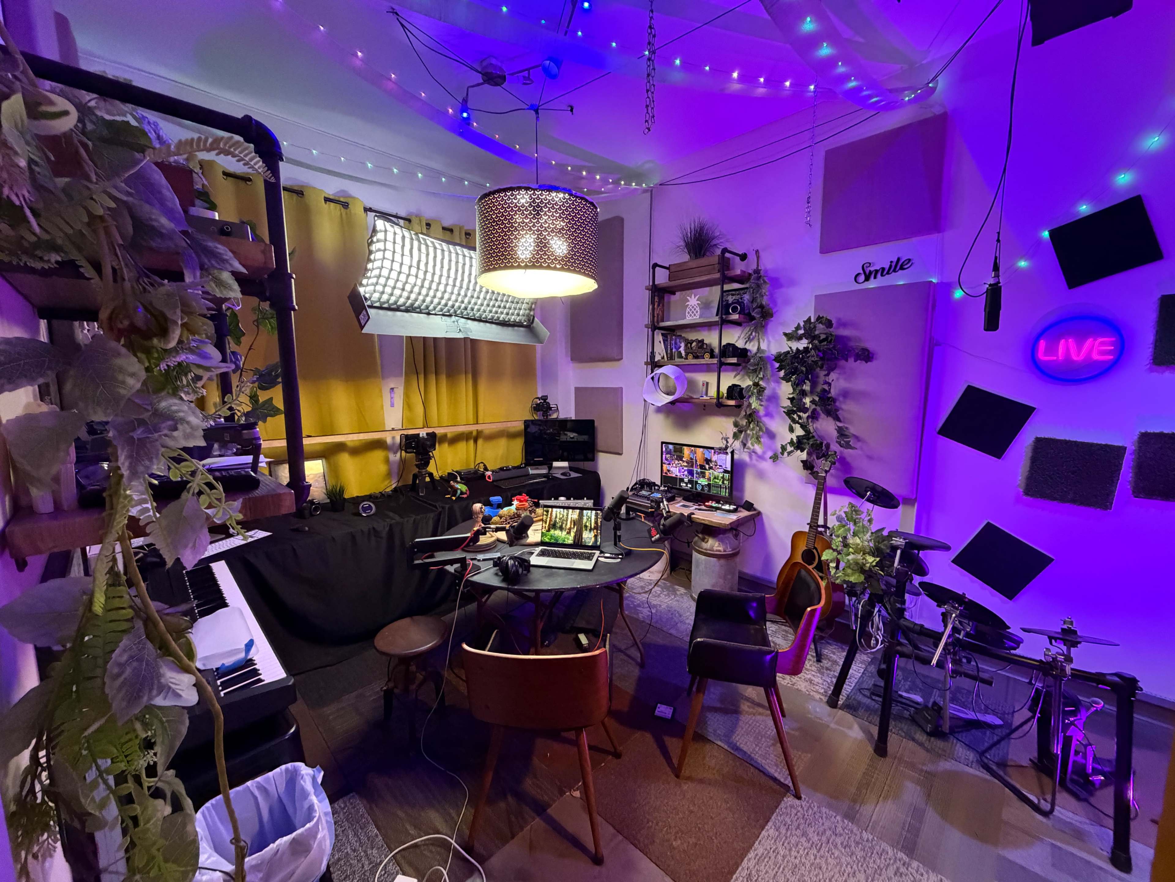 The image shows a vibrant, well-equipped creative studio featuring musical instruments, a table with equipment, and colorful lighting.