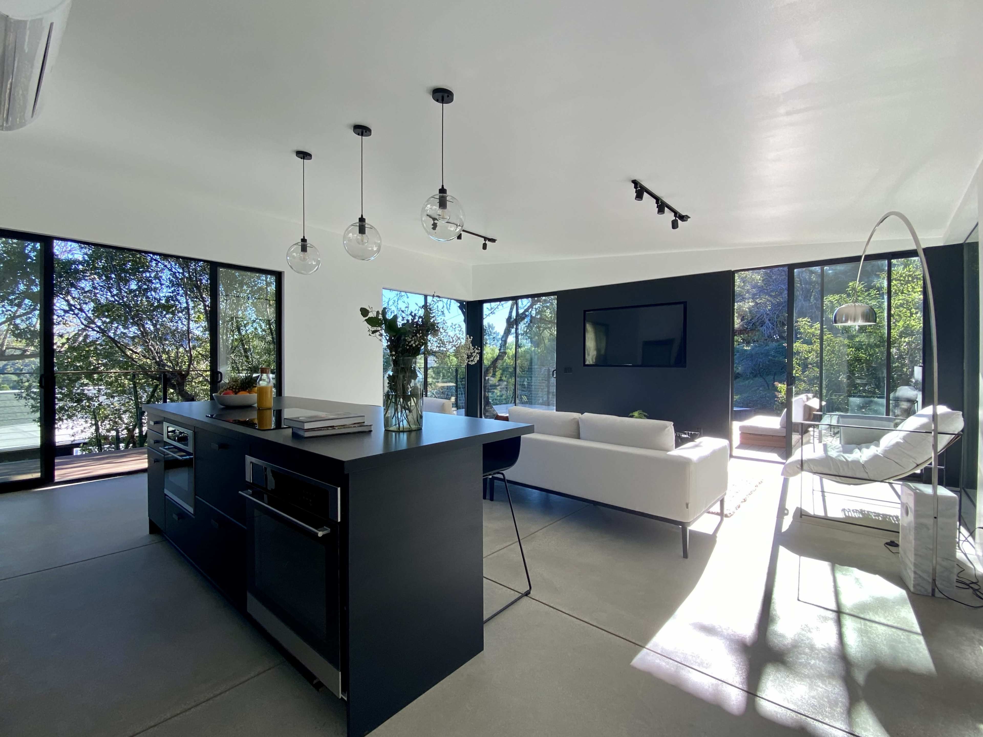 A modern kitchen and living area with large windows that overlook a natural landscape.