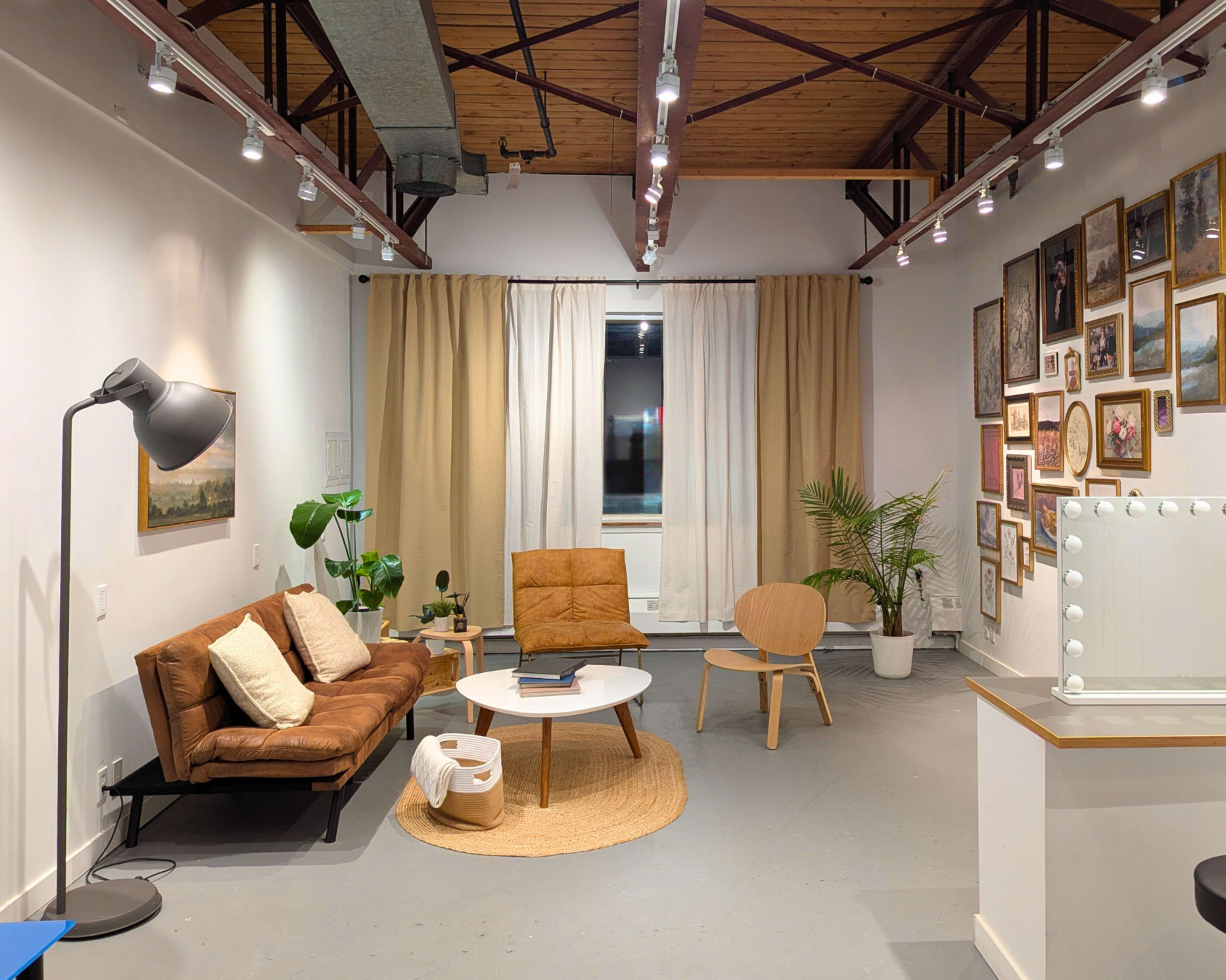 The image shows a modern living space featuring a leather sofa, a round coffee table, a wooden chair, and framed artwork on the walls.