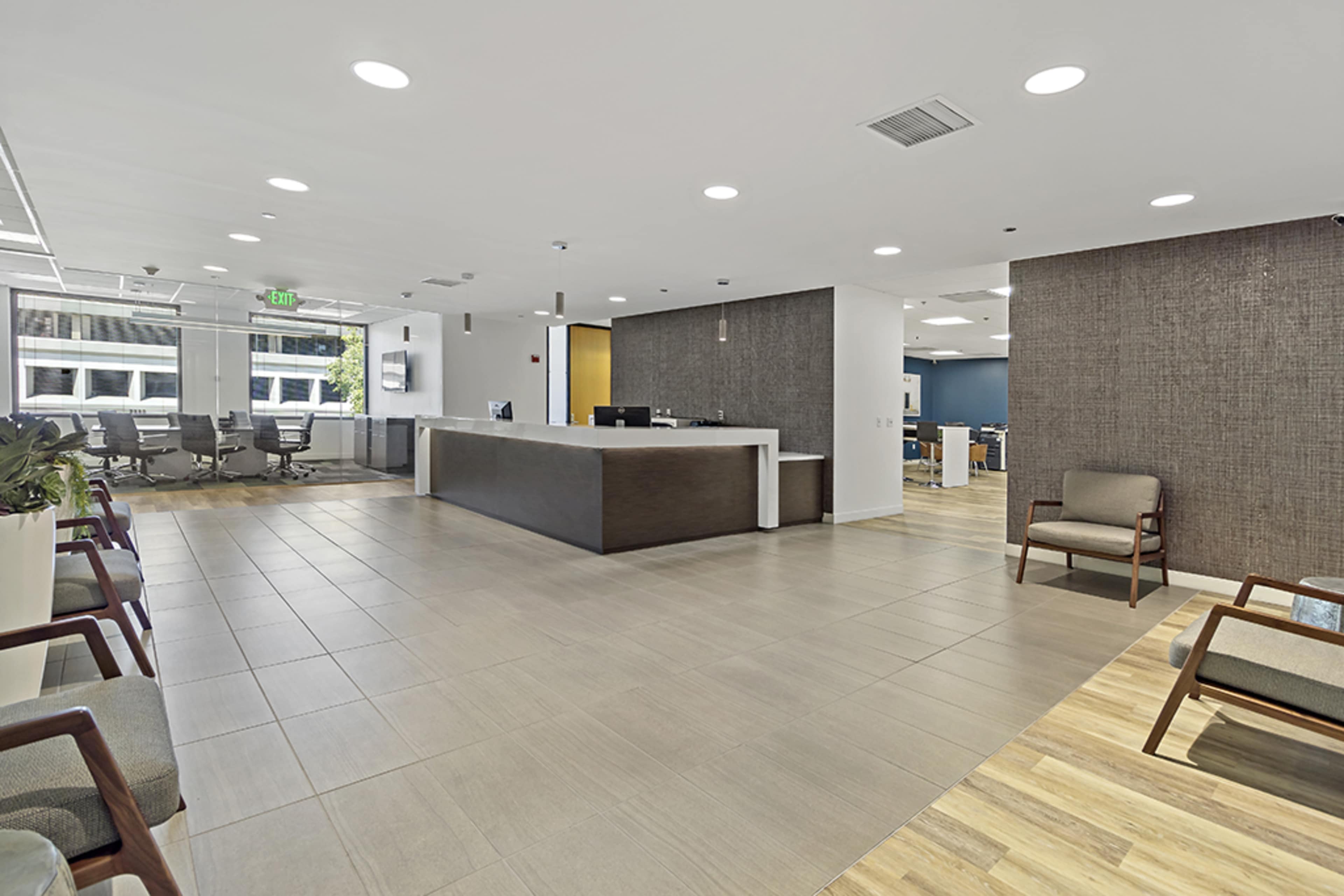 A modern office reception area with a front desk, seating, and an open workspace visible in the background.