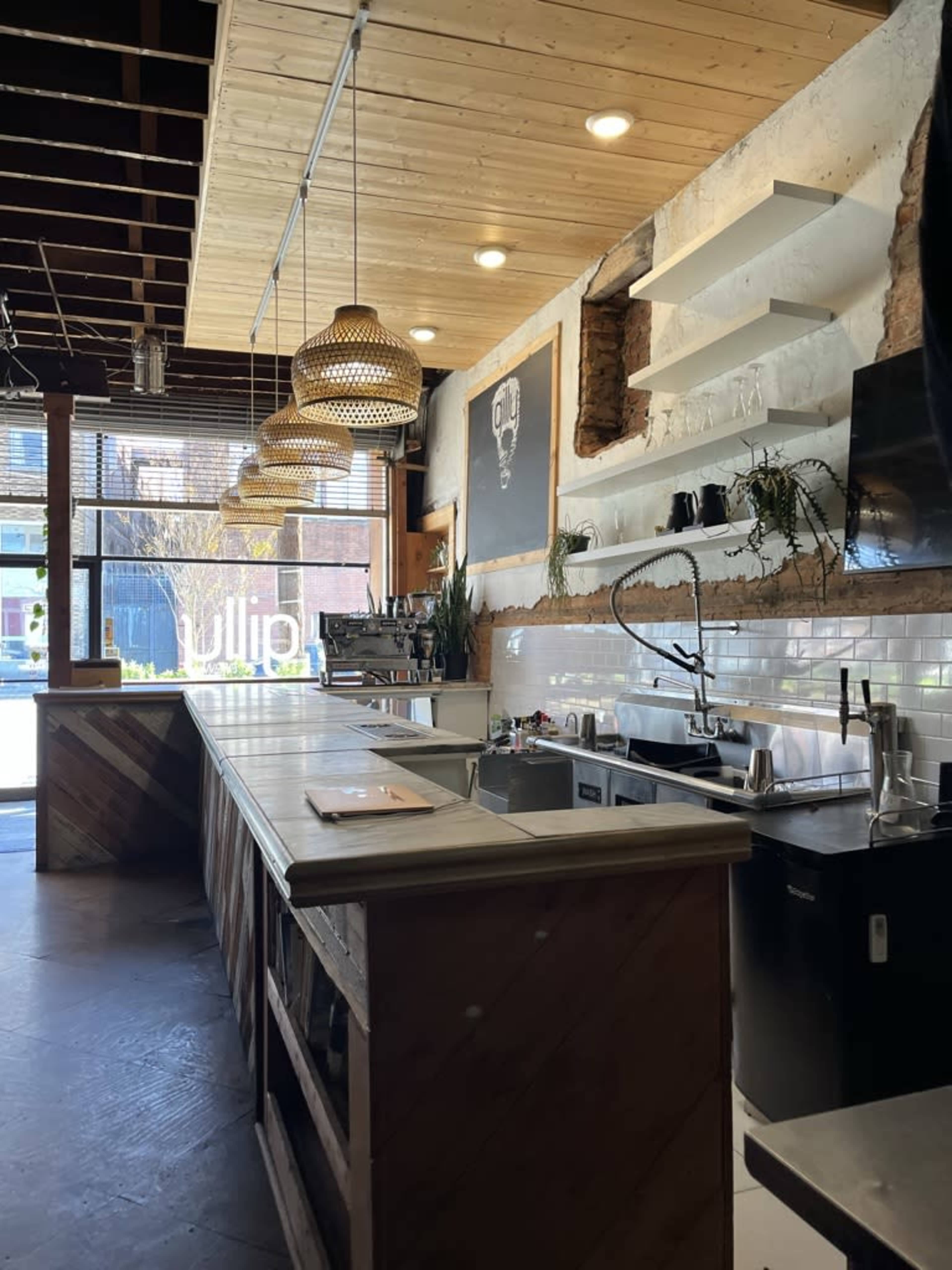 A modern kitchen with a wooden counter, exposed brick wall, and pendant lights hanging from the ceiling.