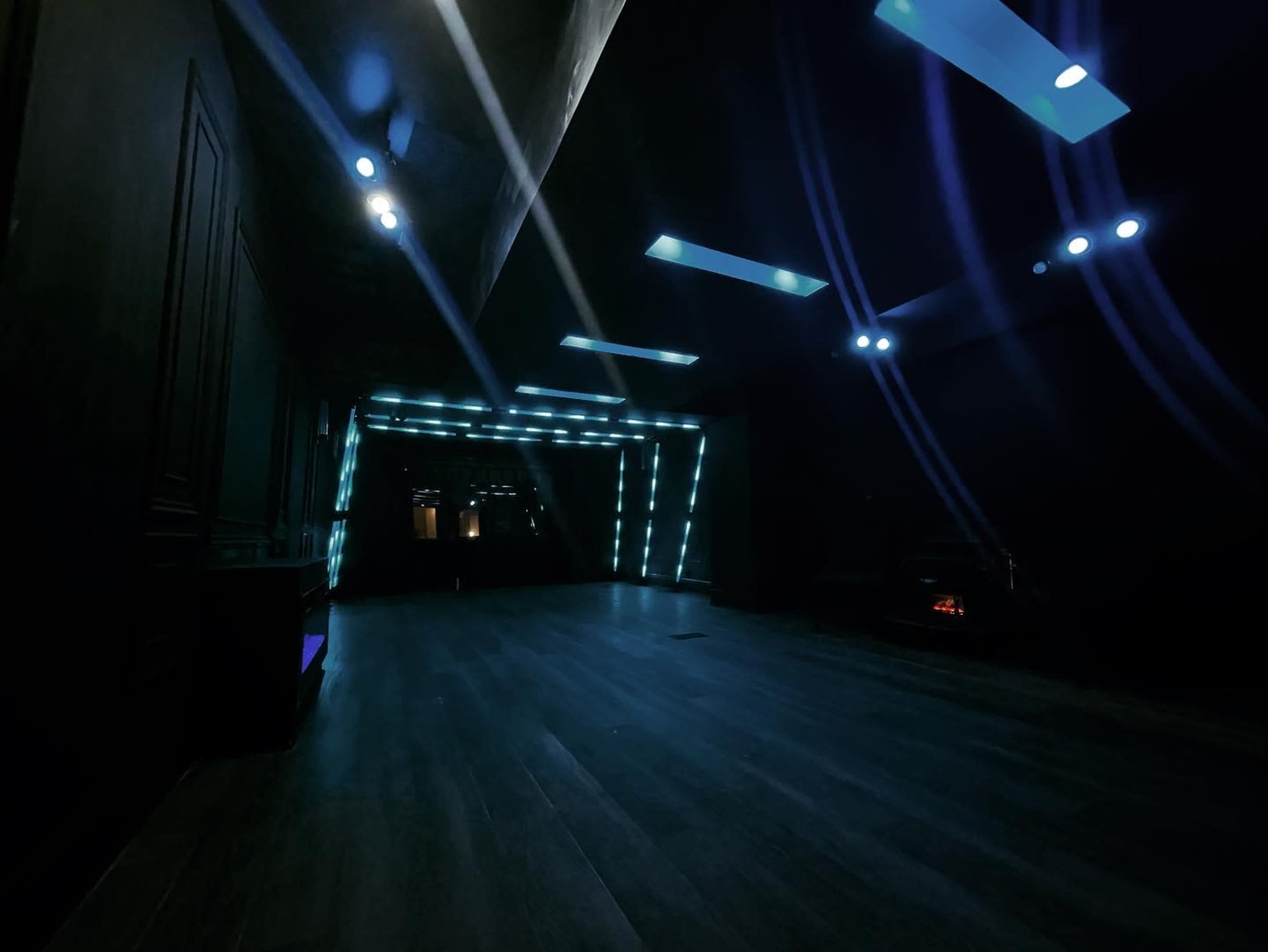 A dimly lit room with dark walls and blue neon lights along the perimeter, creating a modern, sleek atmosphere.