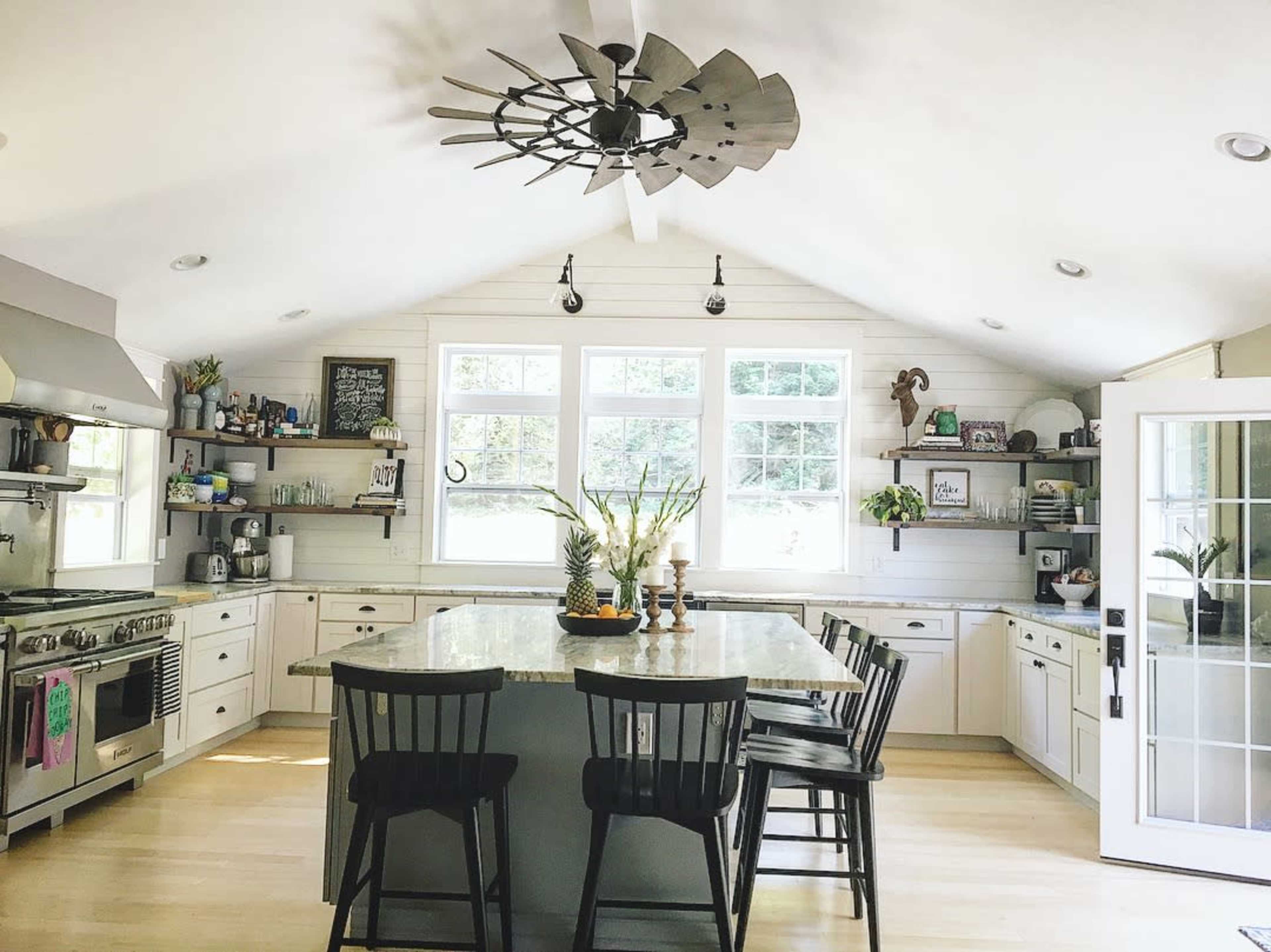 A modern kitchen with a large island, stainless steel appliances, and a vaulted ceiling featuring a decorative fan.