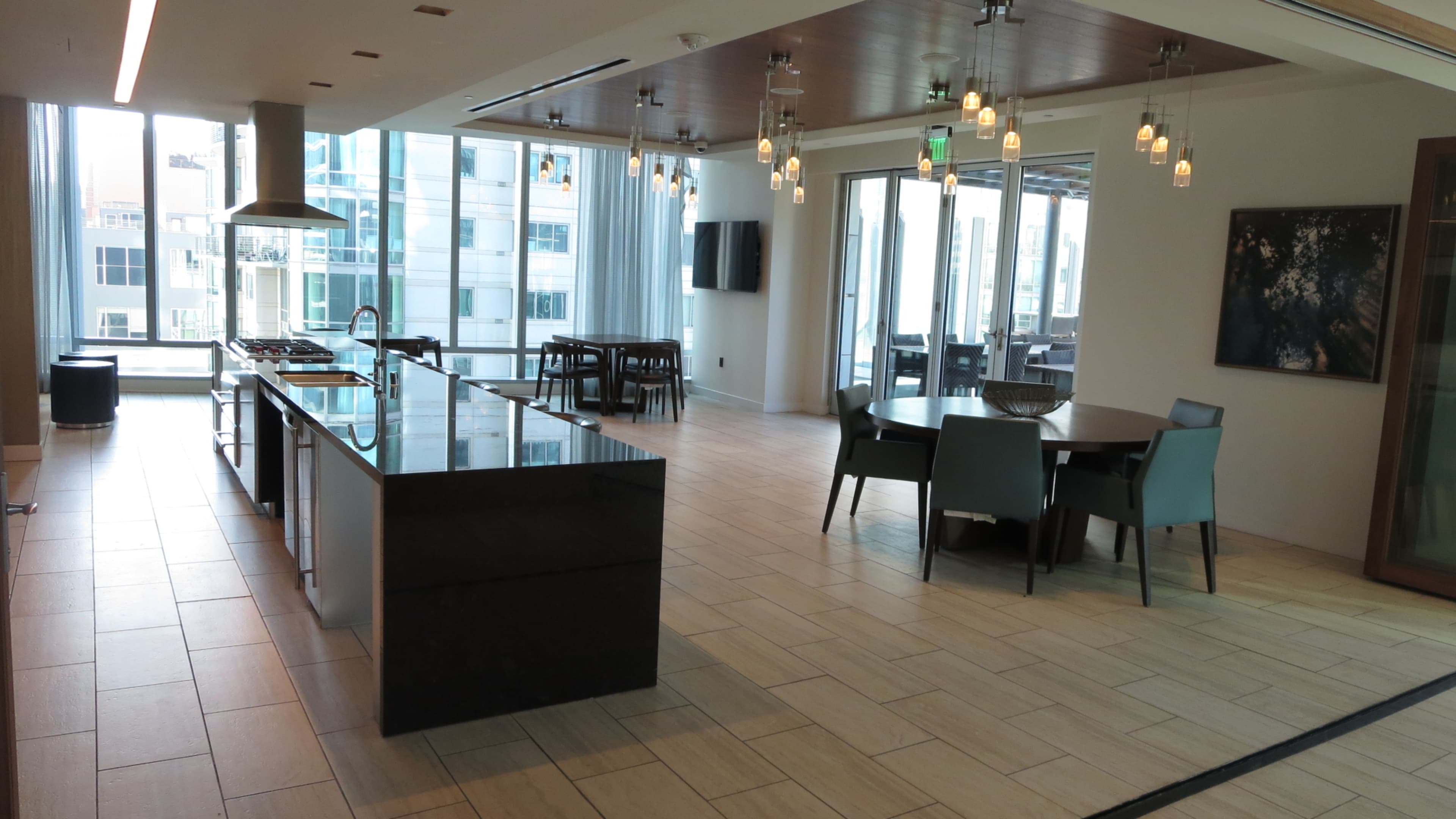 A modern kitchen and dining area with large windows, wooden ceiling lights, and a minimalist design.
