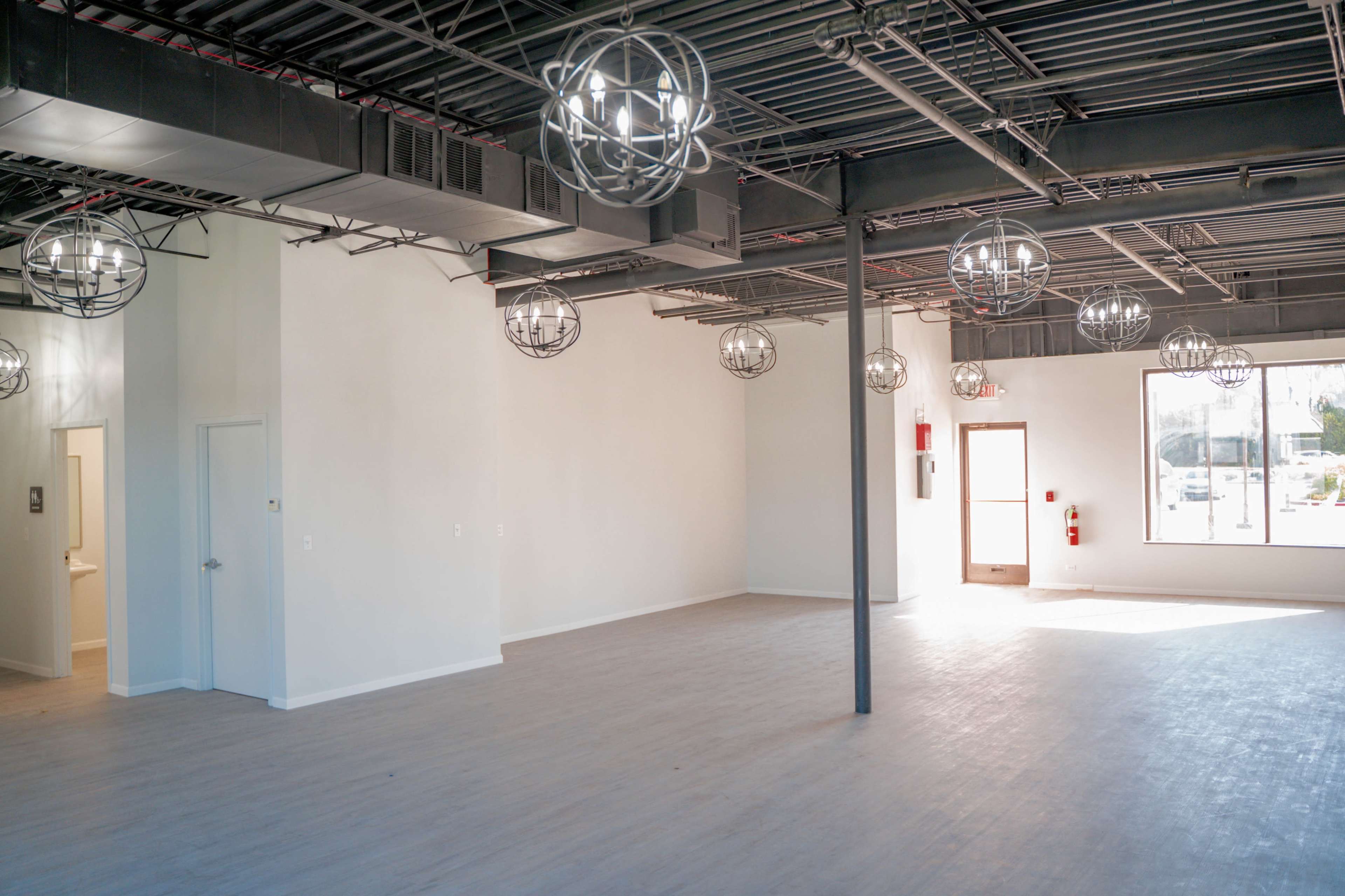A spacious, empty interior with pendant light fixtures and large windows allowing natural light to enter.