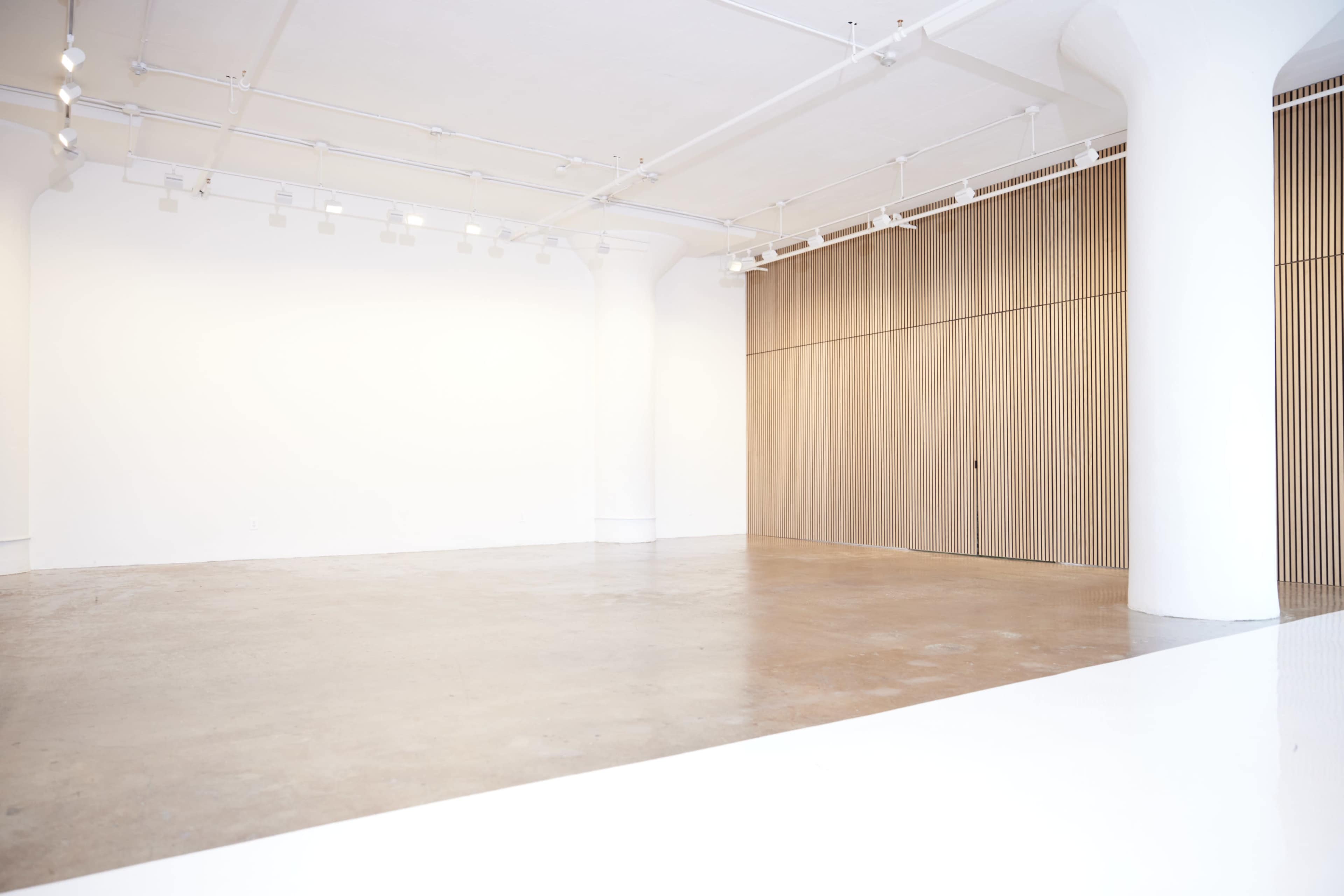 An empty interior space with polished concrete flooring and a wall featuring vertical wooden slats.