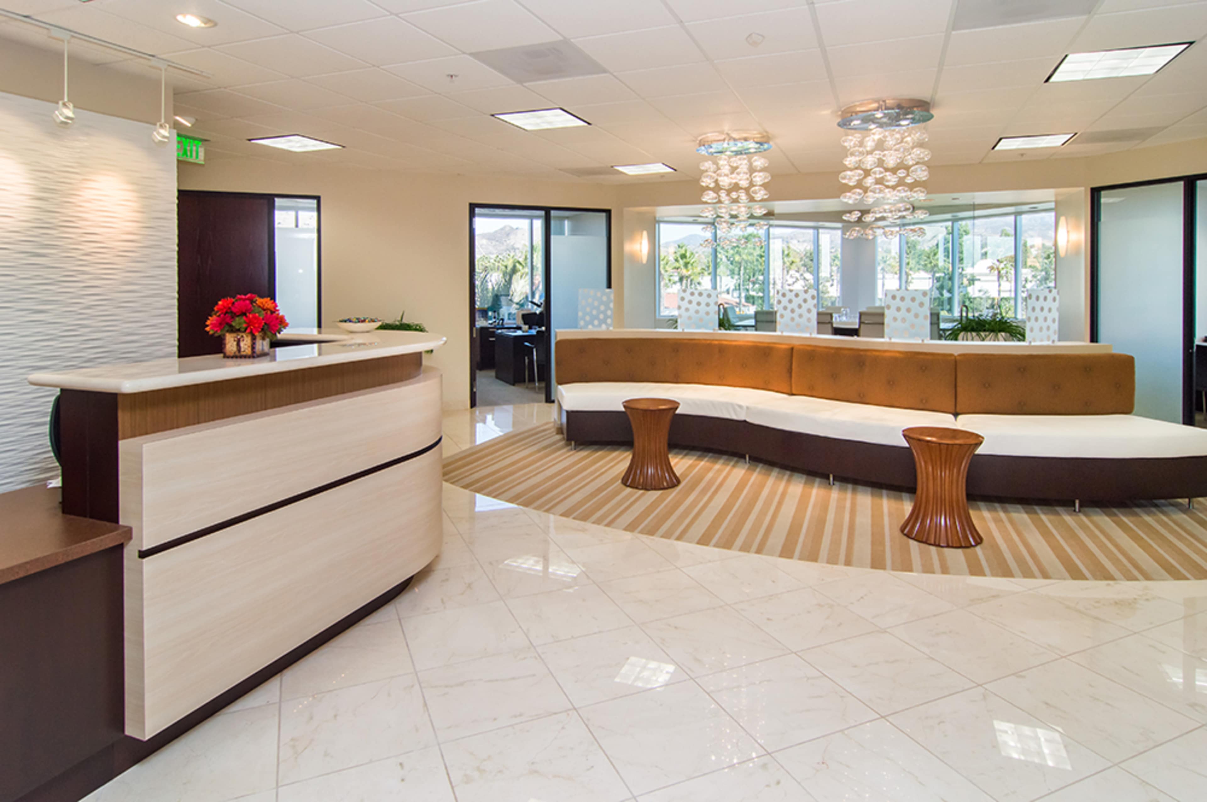 A modern reception area with a curved seating arrangement, a front desk, and large windows providing a view of the outside.