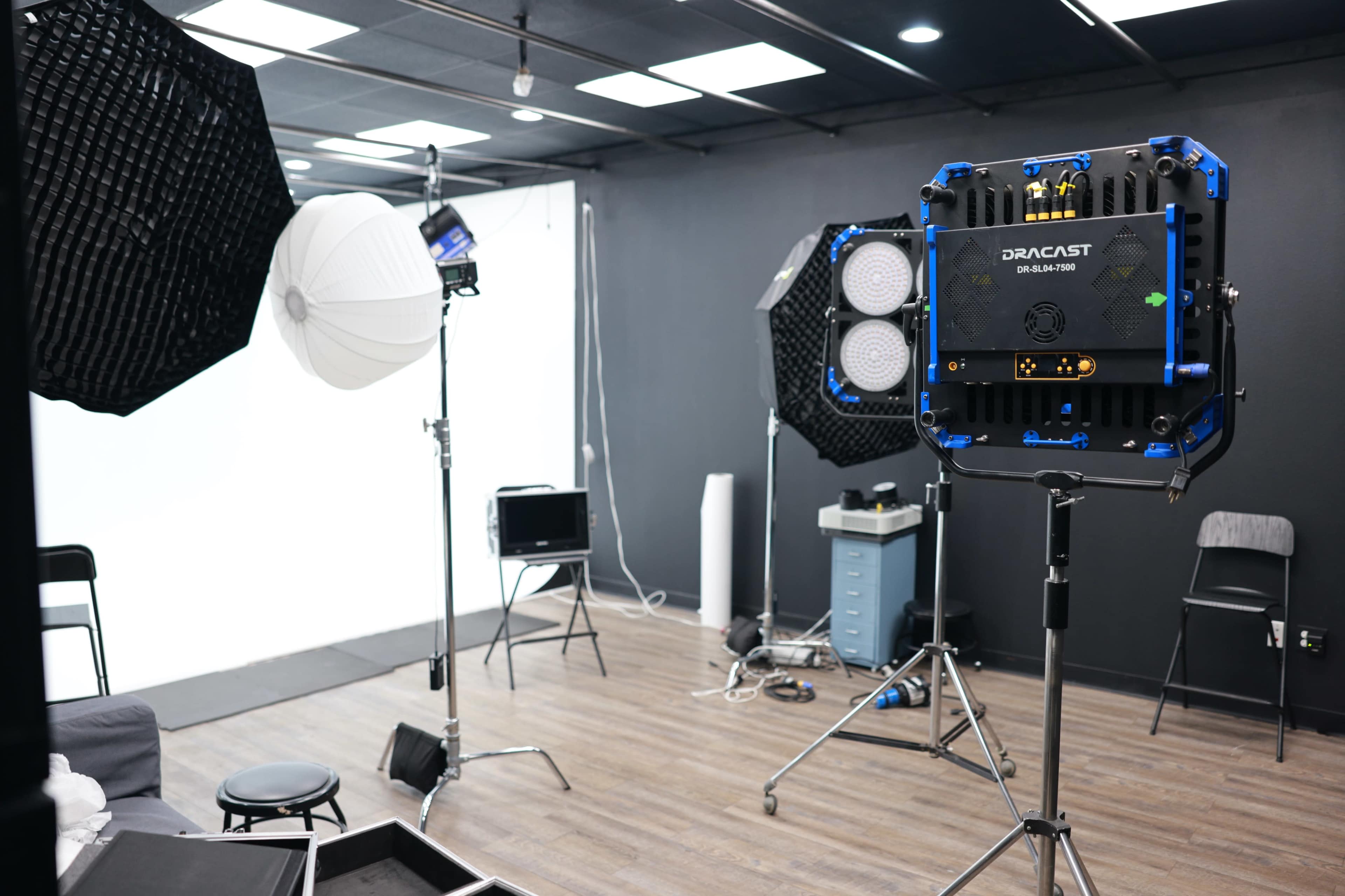 A photography studio is set up with various lighting equipment and reflectors arranged around a backdrop.