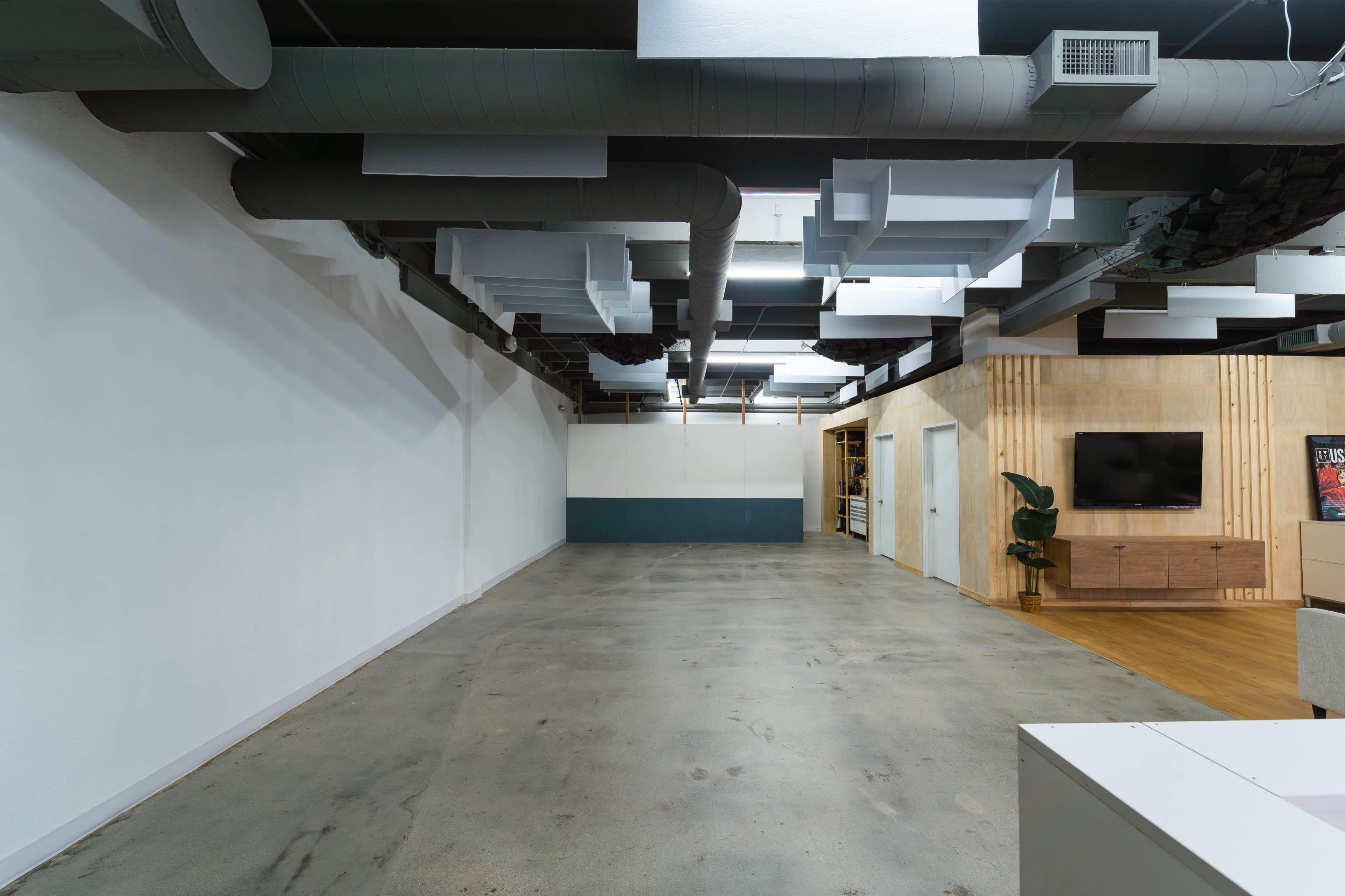 The image shows a spacious, contemporary office interior with exposed ductwork and minimalist furniture.