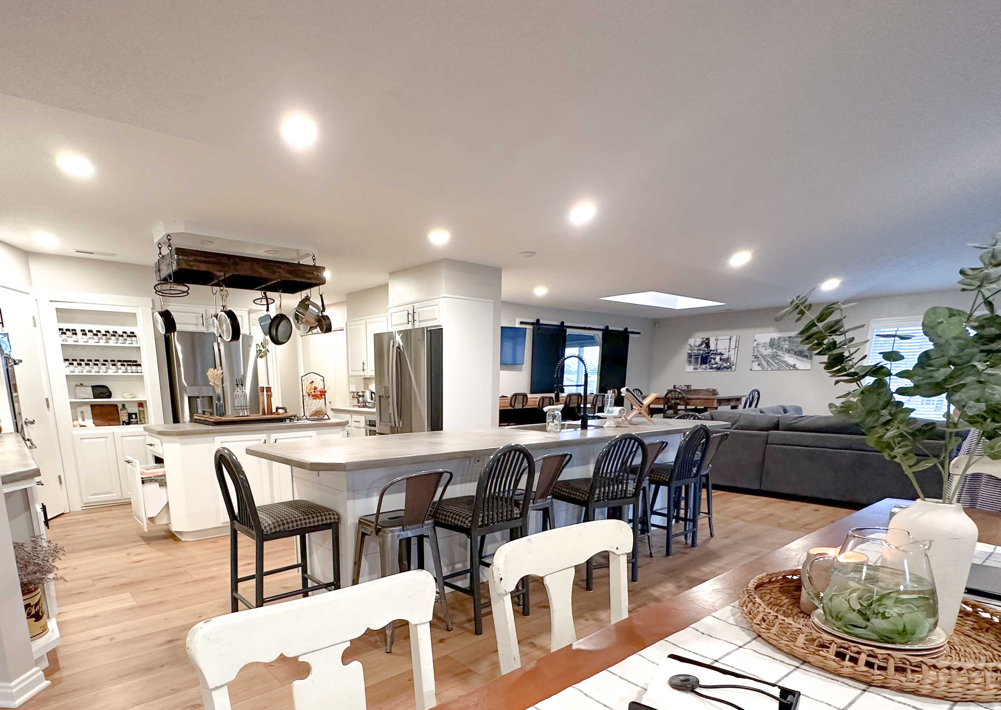A spacious, modern kitchen with an island, bar stools, and open access to a living area furnished with a couch and decorative elements.