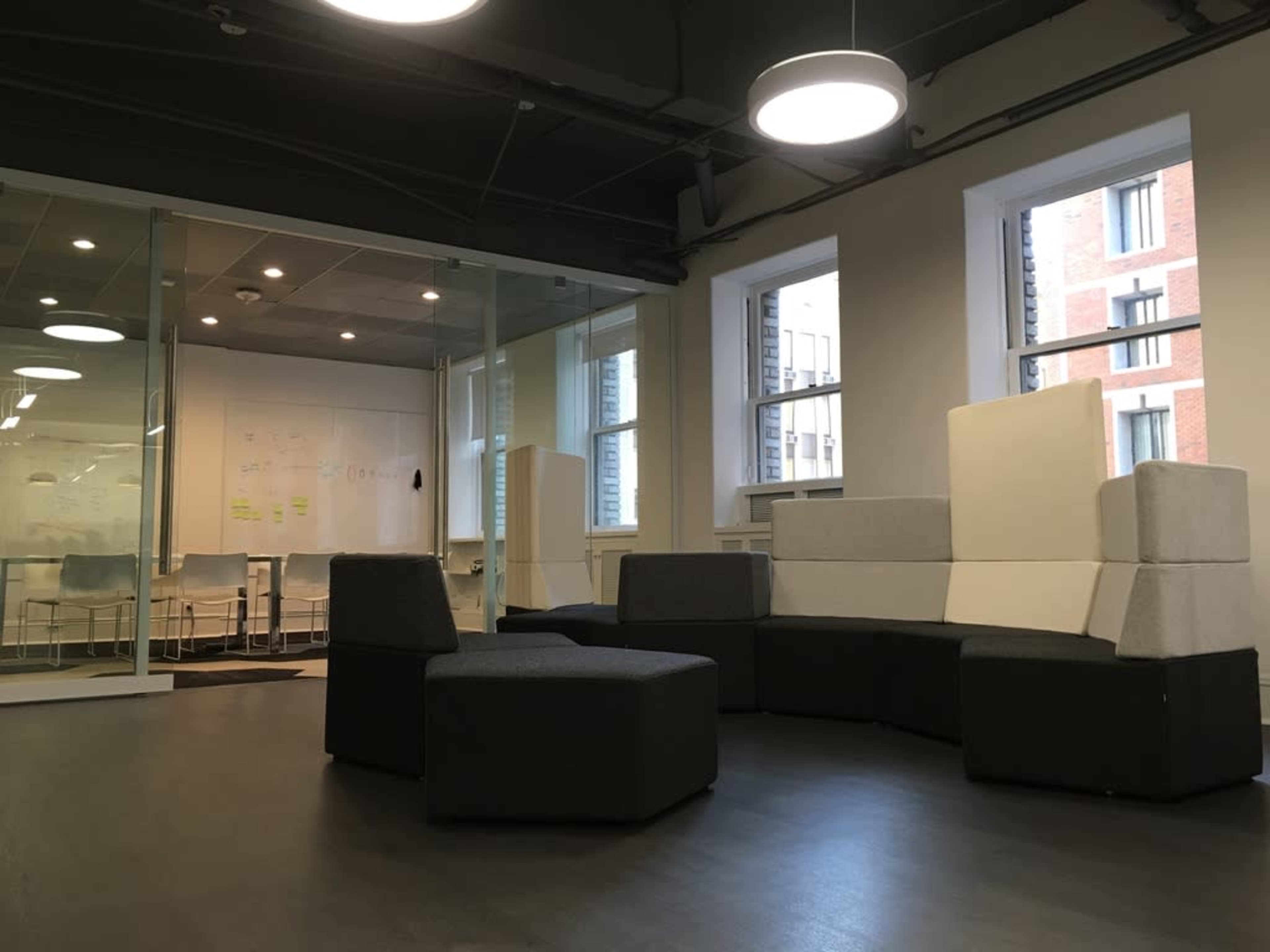 A modern office space with a seating arrangement featuring modular, multi-colored furniture and large windows providing natural light.