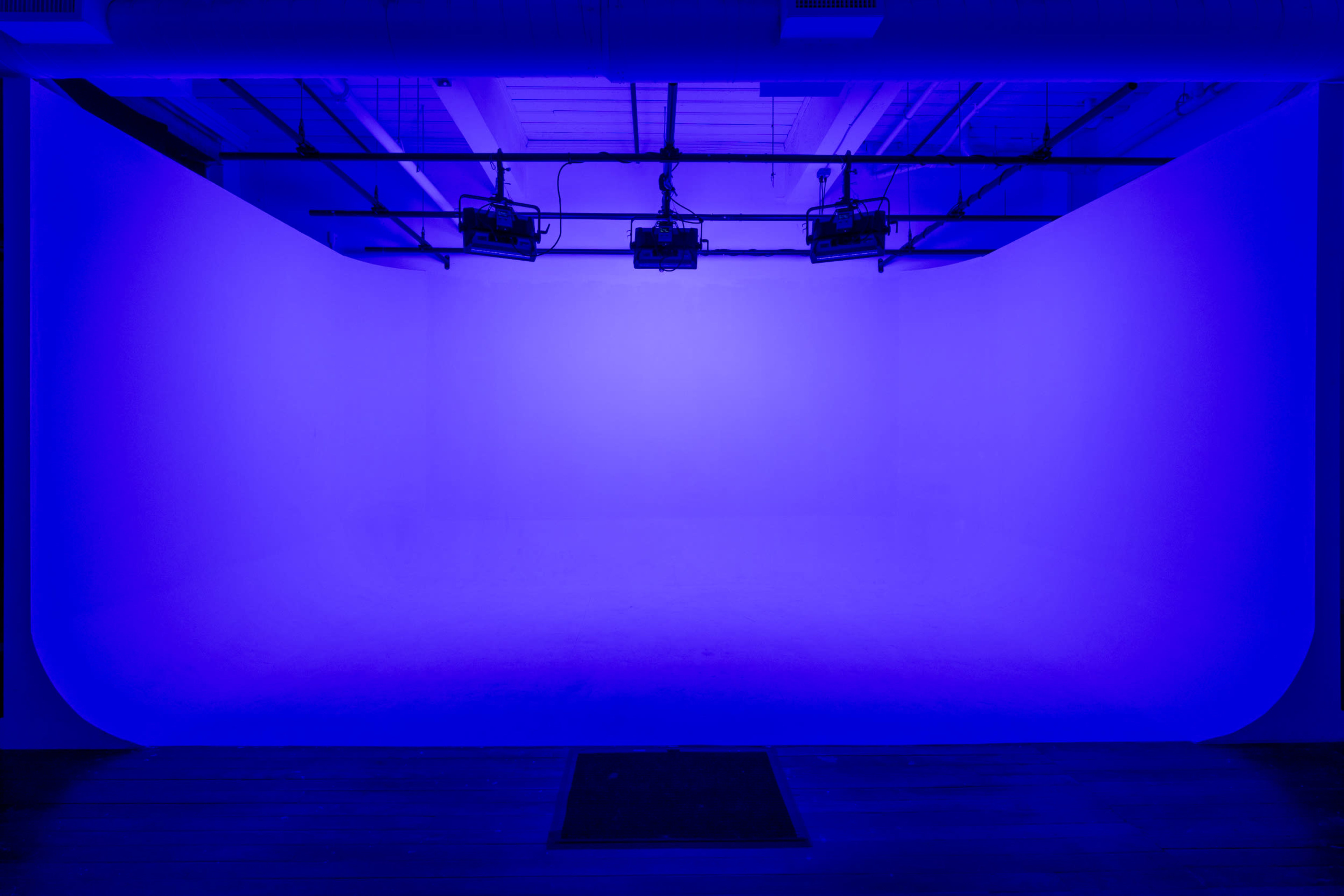 A studio space with a smooth, bright blue backdrop and overhead lighting.