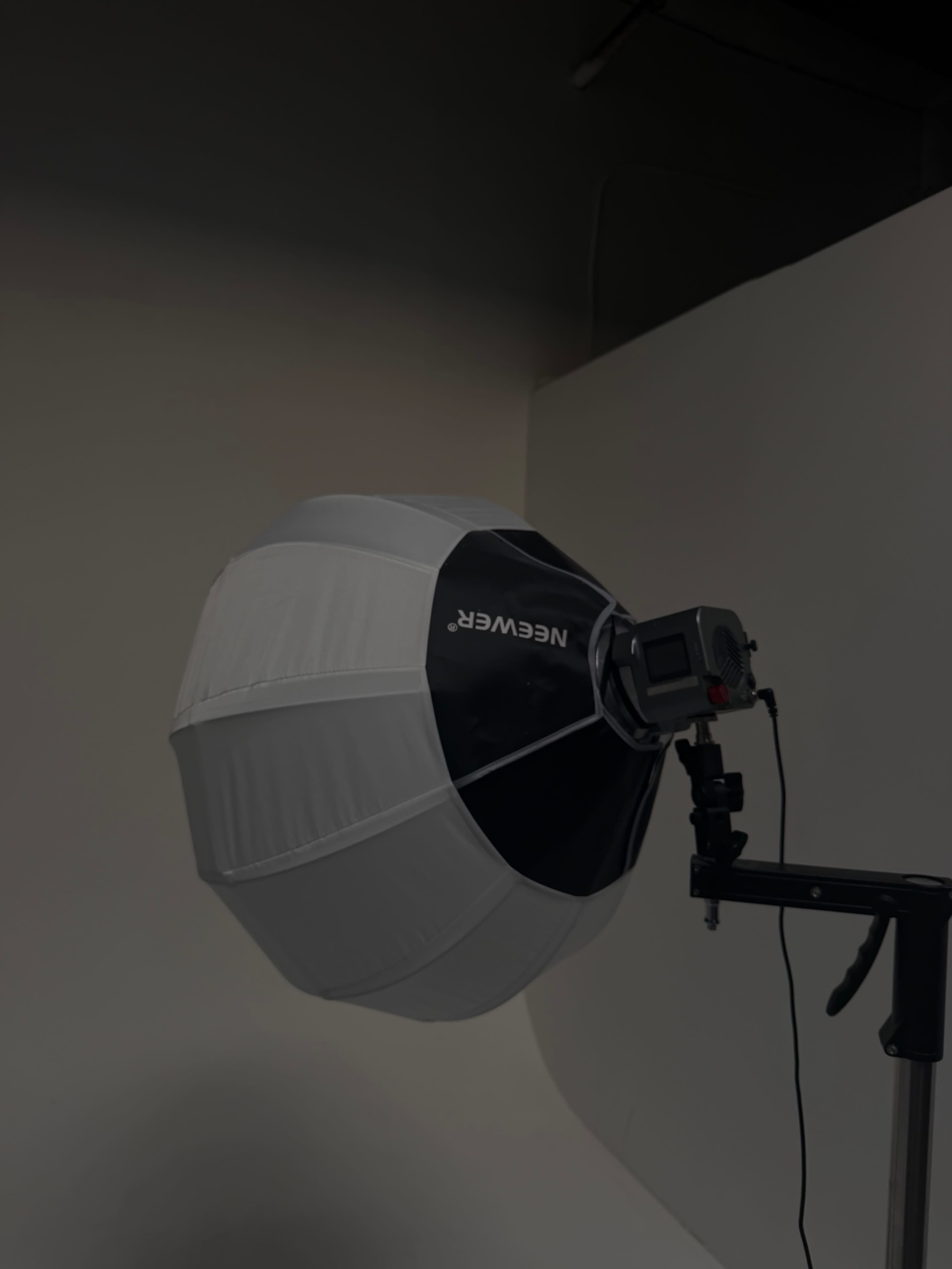 A softbox with a black and white exterior is mounted on a light stand in a photography studio.
