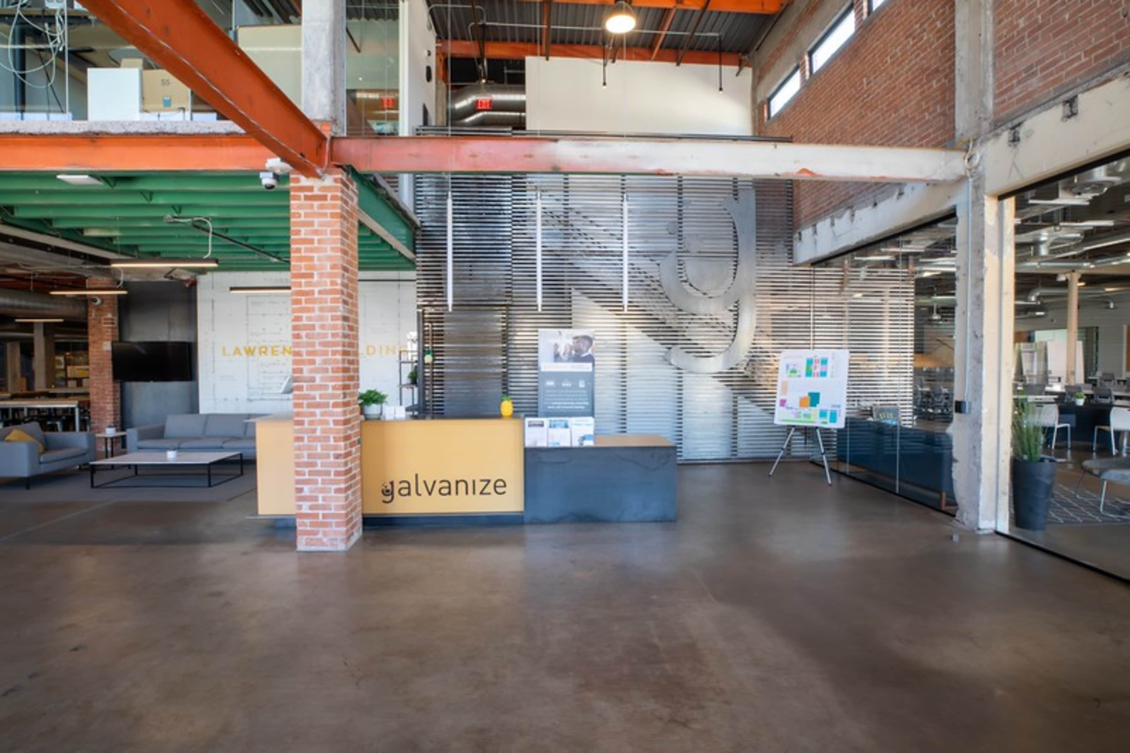 The image shows a modern office lobby with a reception desk and a wall featuring a wavy metal design, along with exposed brick and beams.