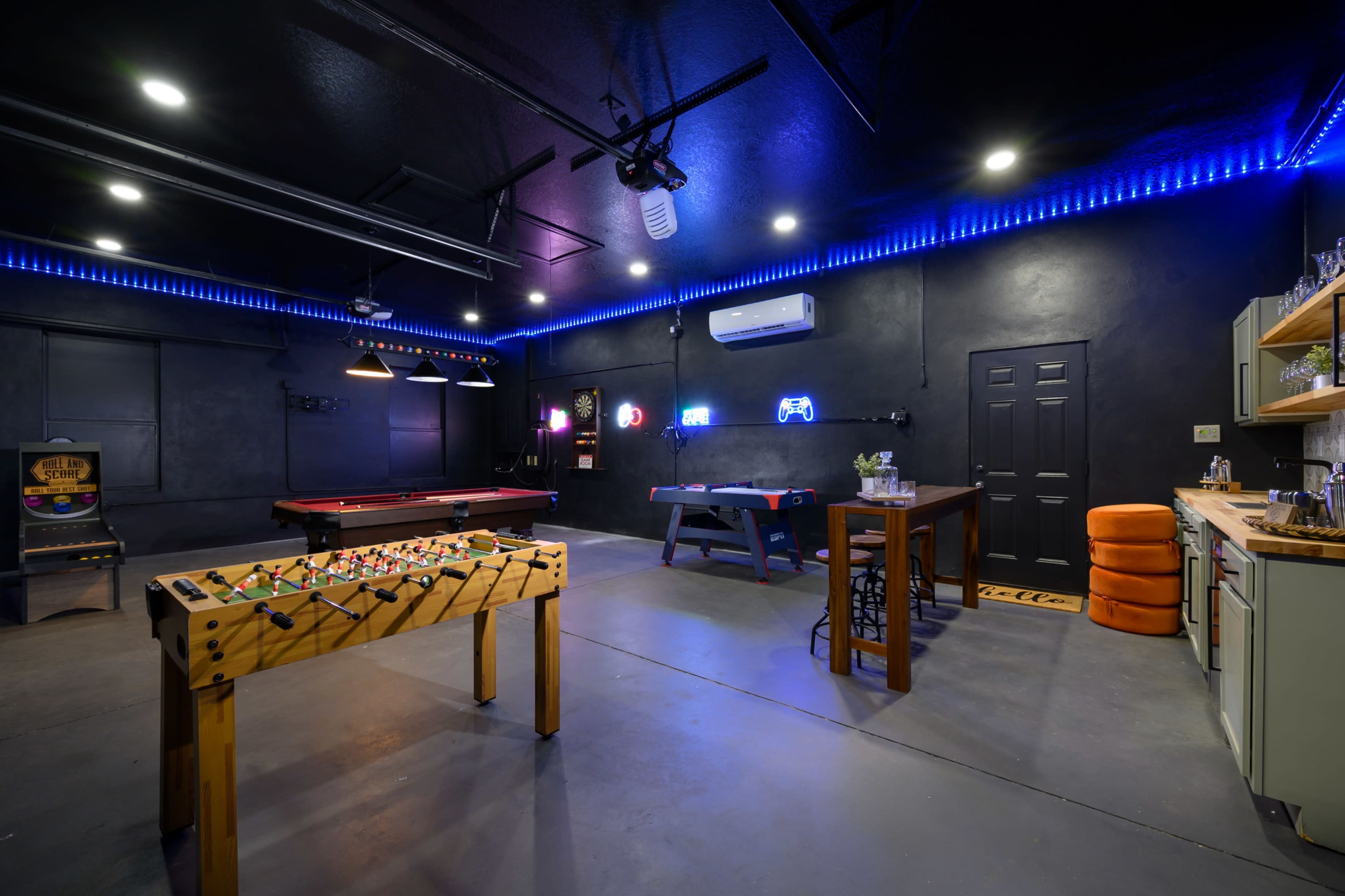 A game room featuring a foosball table, a pool table, and neon lighting on the walls.