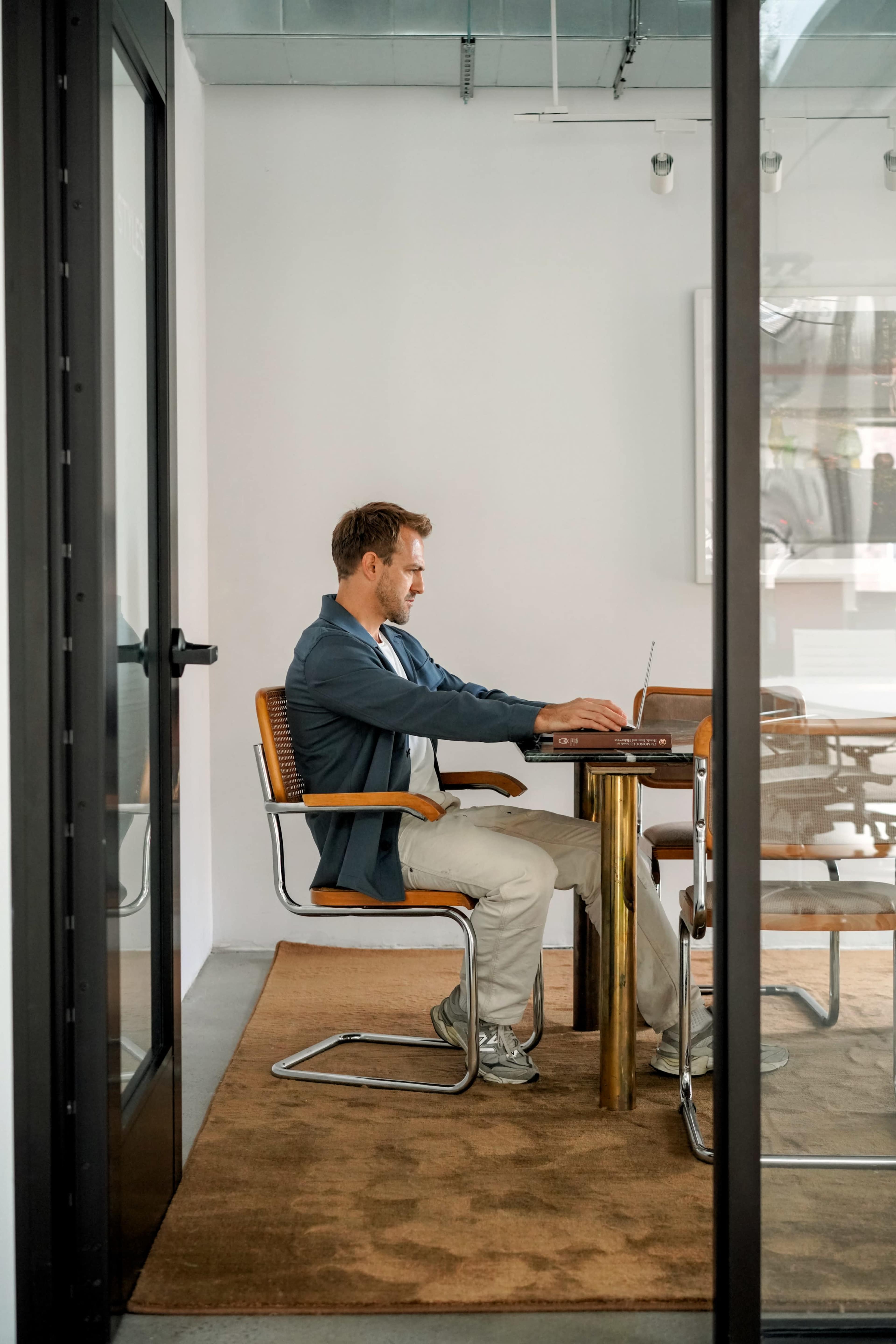 A man is seated at a desk working on a laptop in a modern office setting.